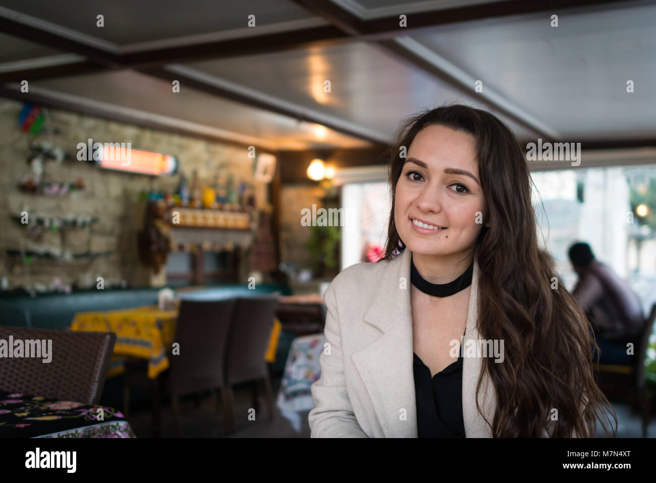 Incontro con la bella donna orientale si siede in un semplice cafe. Giovane ed elegante brunette sorridente e cercando nella fotocamera in un ristorante orientale Foto Stock