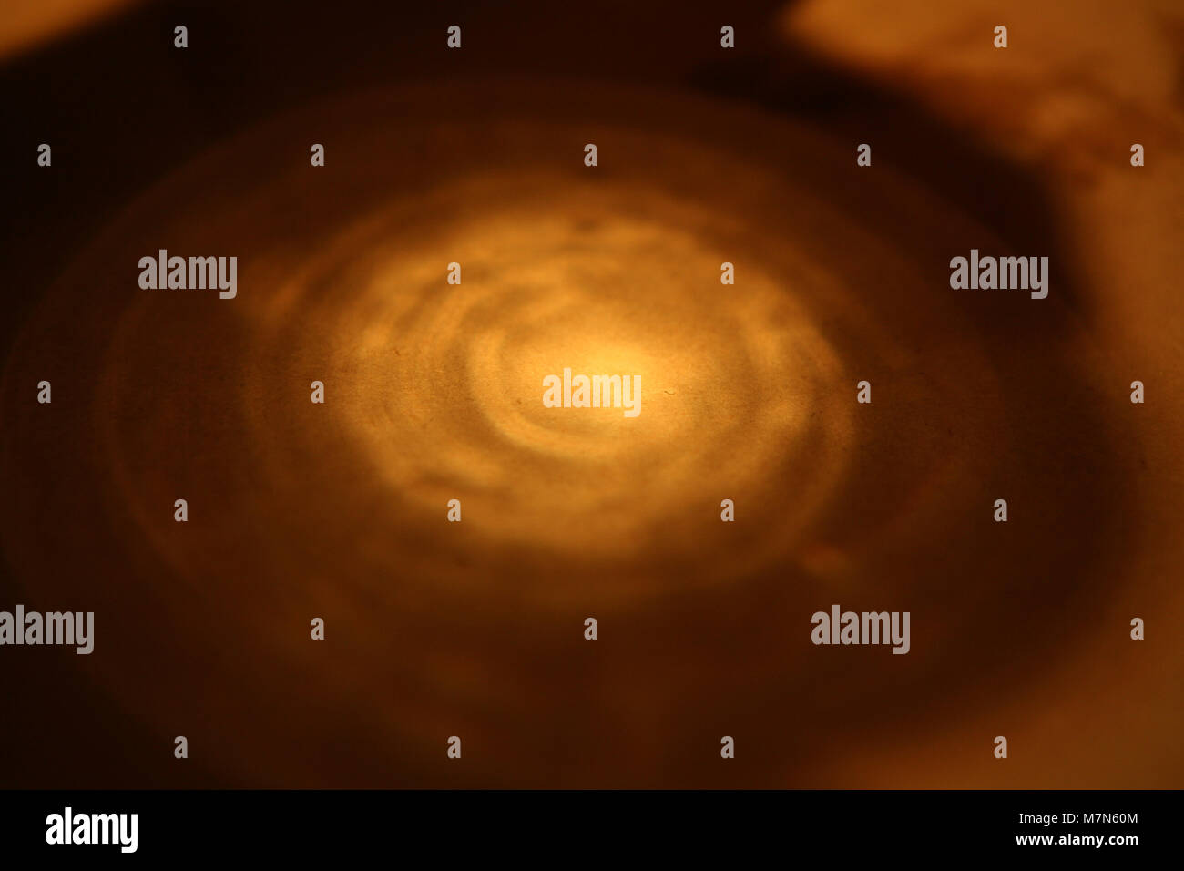 La riflessione della luce nella parte di fondo di un bicchiere di acqua su un tavolo Foto Stock