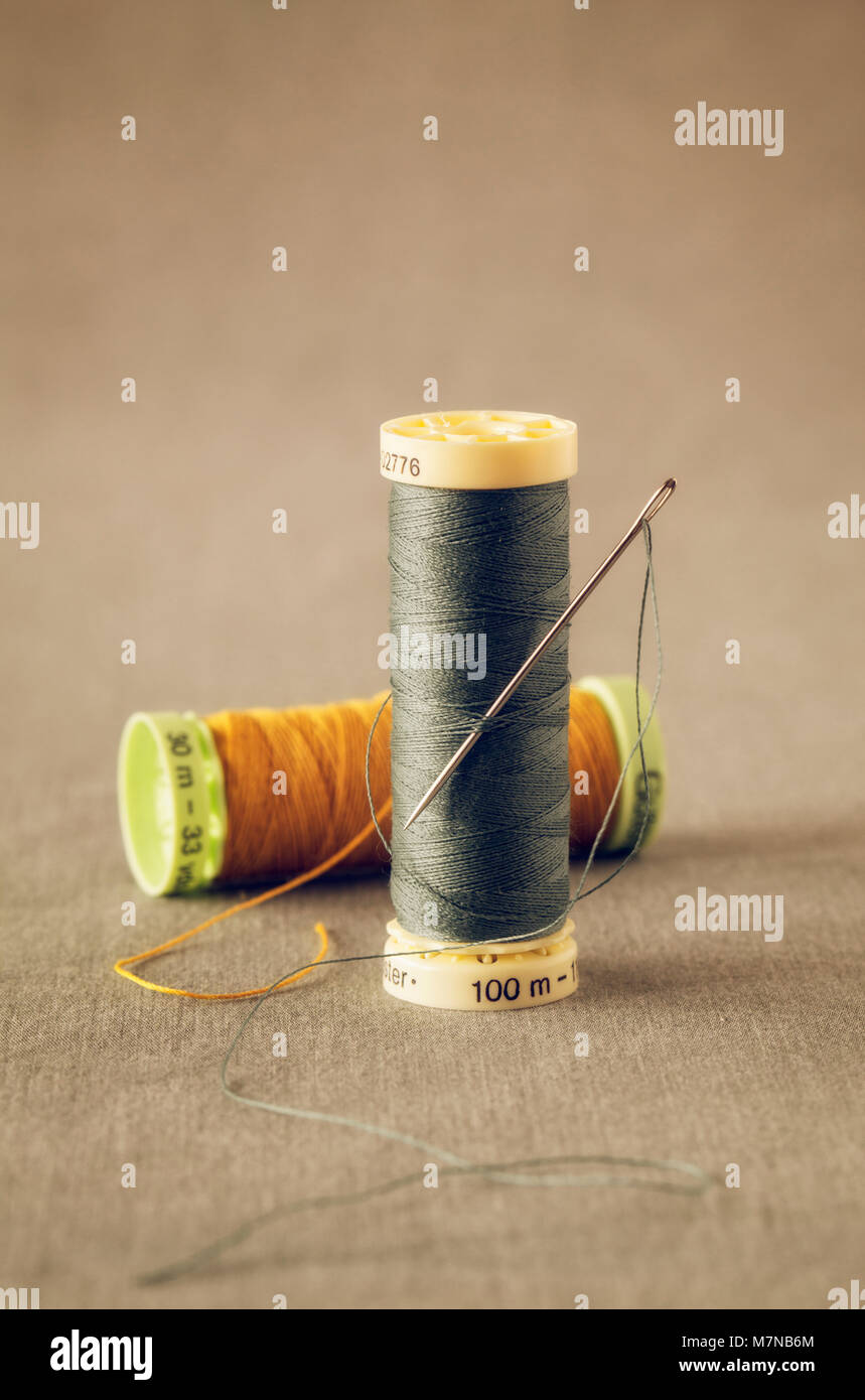 Due rotoli di fili colorati con ago di cucitura Foto Stock