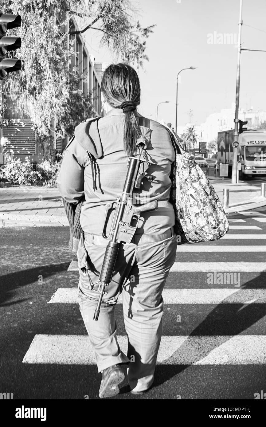 Il sovrappeso israele soldato femmina trasportare armi e shopping bag Foto Stock