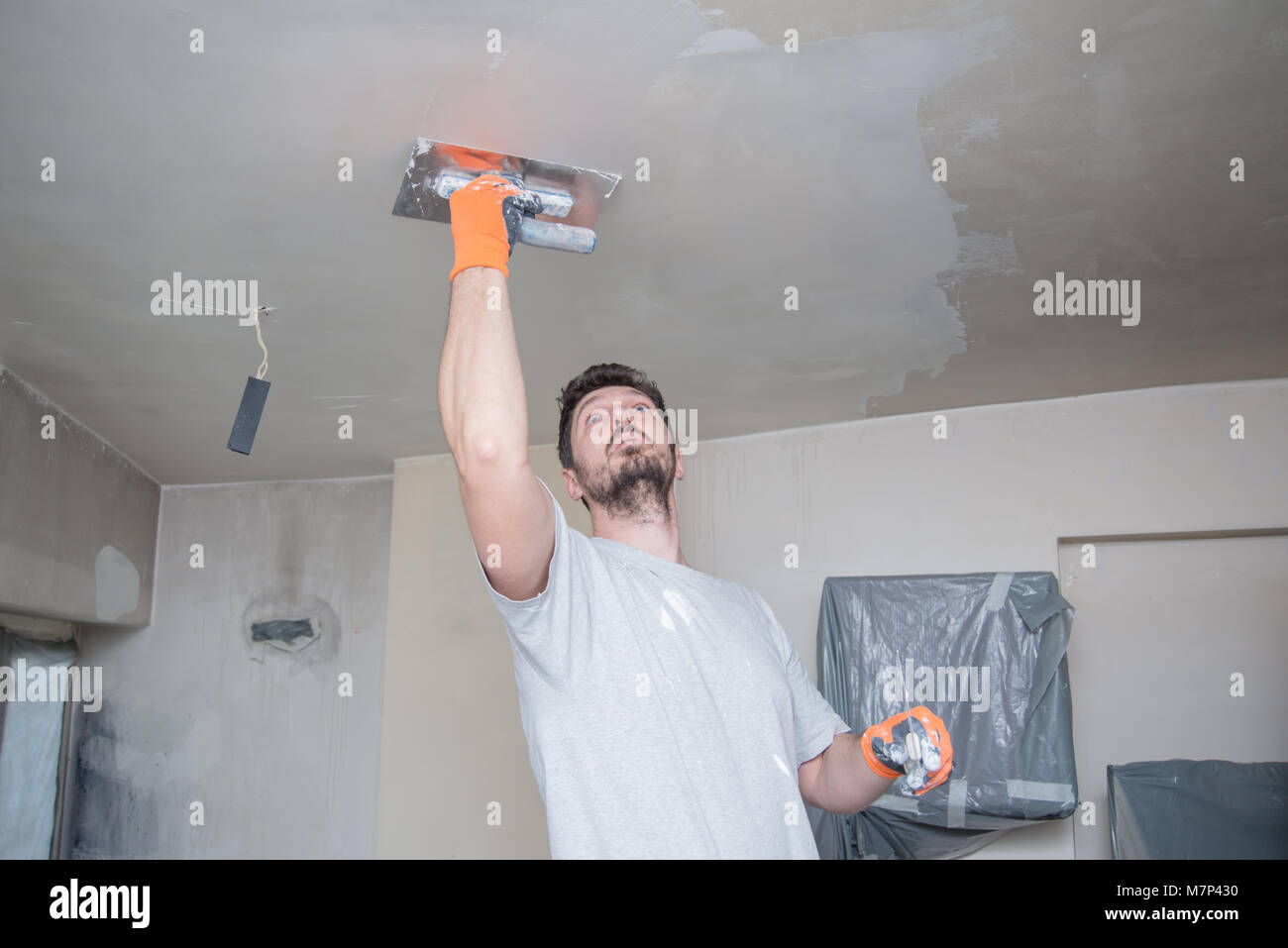Lavoratore soffitto intonacatura Foto Stock
