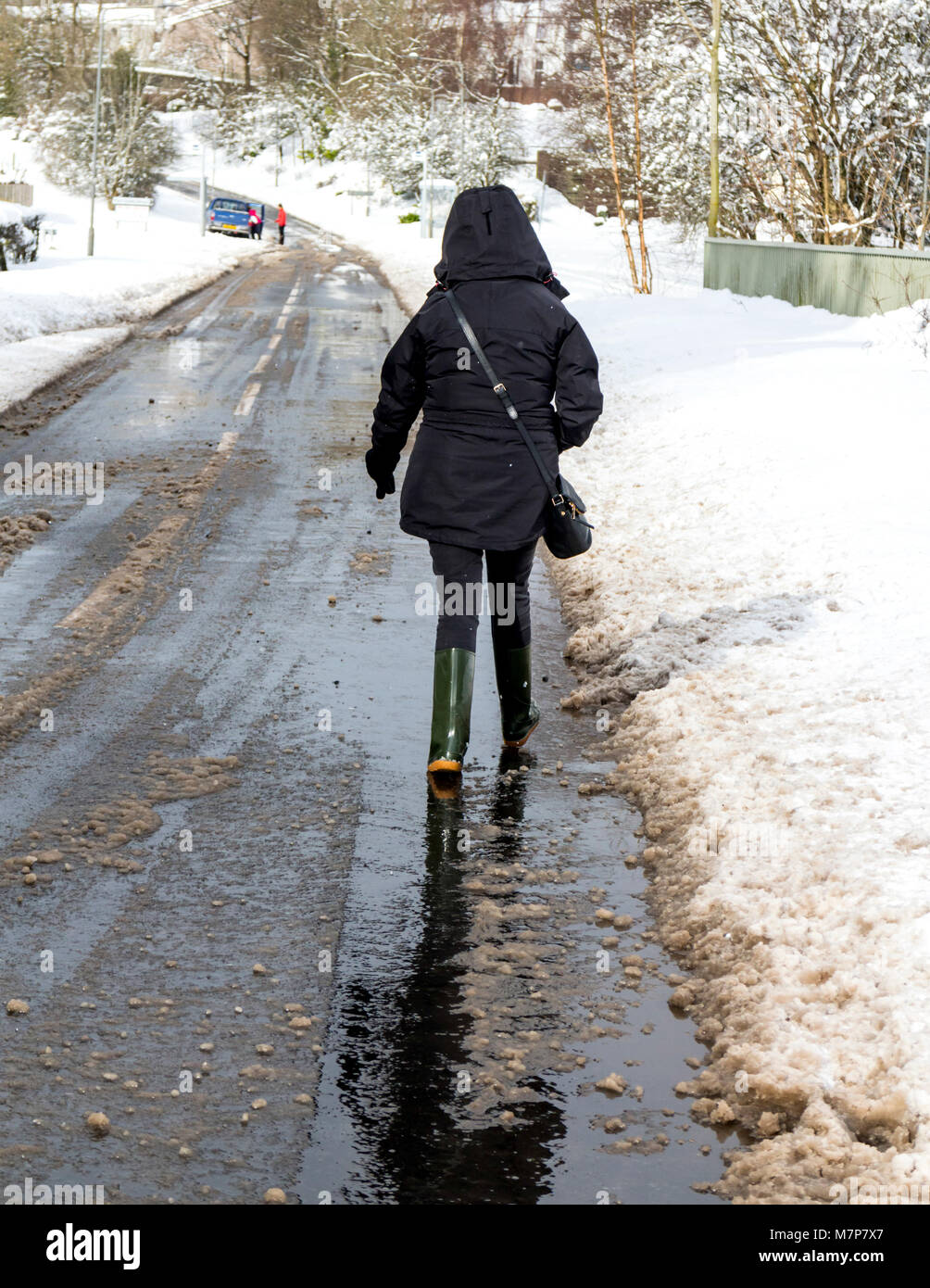 Donna costretto a camminare su una strada cancellati a causa della neve che ricopre il marciapiede, Scozia. Foto Stock