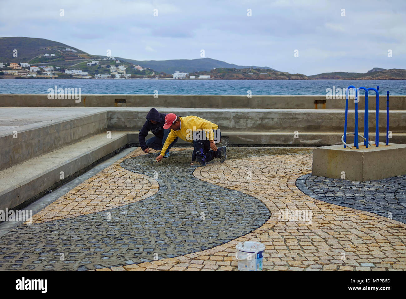 Finikas Bay : 12 marzo . Stone Muratori preparazione del mosaico di pietra design all'aperto in un luogo pubblico square.. Finikas, 12 marzo 2018, Syros, Grecia. Foto Stock