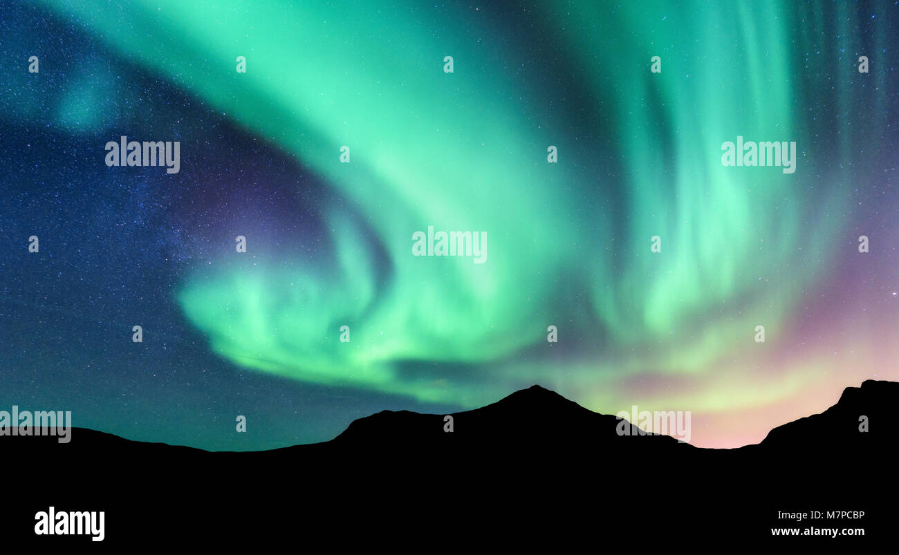 Aurora boreale e silhouette di montagne. Isole Lofoten in Norvegia. Aurora. Verde e viola luci del nord. Cielo con le stelle e le luci polari. Notte Foto Stock