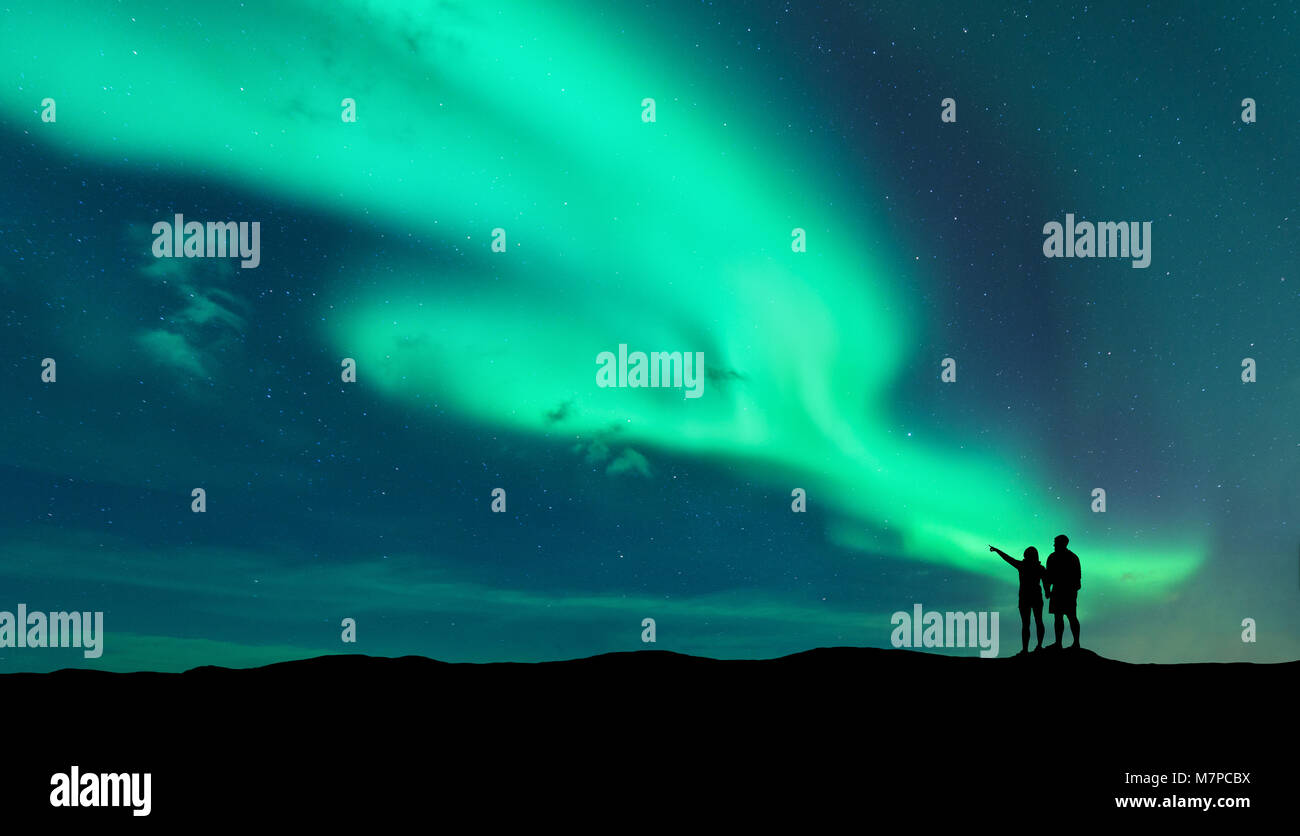 Aurora boreale e silhouette di standing l uomo e la donna che puntare il dito sulle luci del nord. Isole Lofoten,Norvegia. Aurora. Cielo con le stelle e po Foto Stock