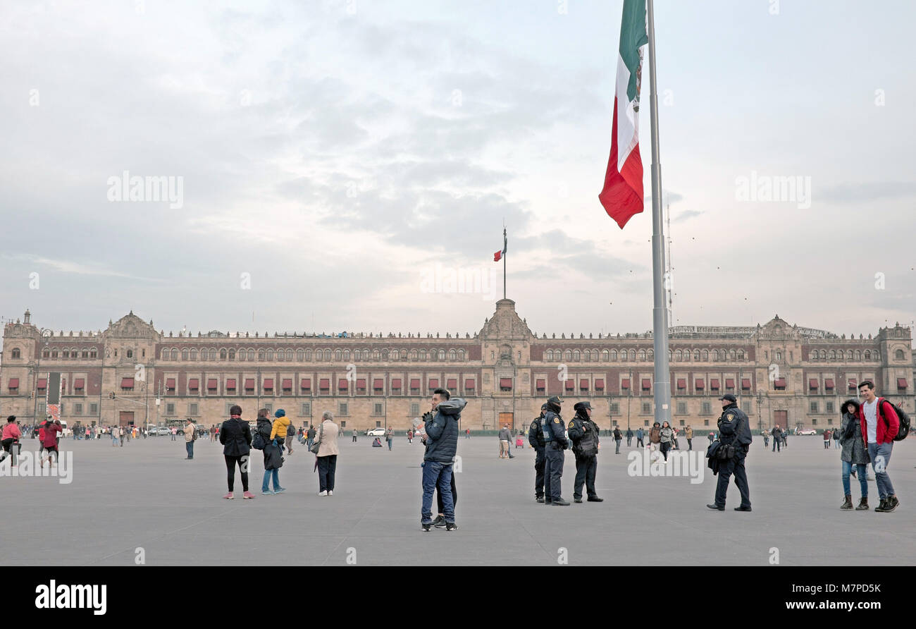 La gente passeggia per la Plaza de la Constitucion con il Palazzo Nazionale sullo sfondo della piazza principale di Città del Messico. Foto Stock