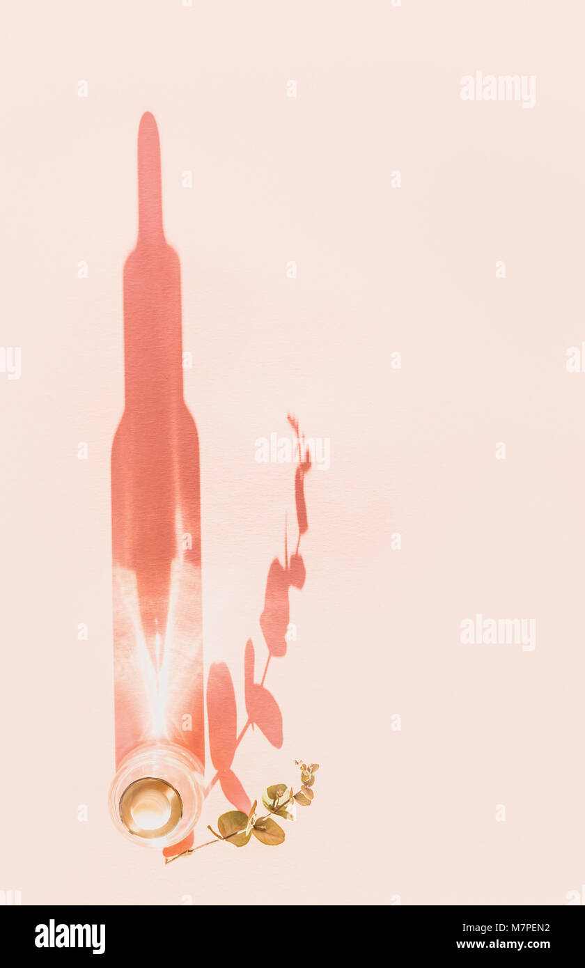 Vista superiore della naturale prodotto cosmetico con lunga ombra in una bottiglia di vetro con contagocce. Il siero prodotto per la cura della pelle sul rosa pastello con sfondo spazio copia. Foto Stock