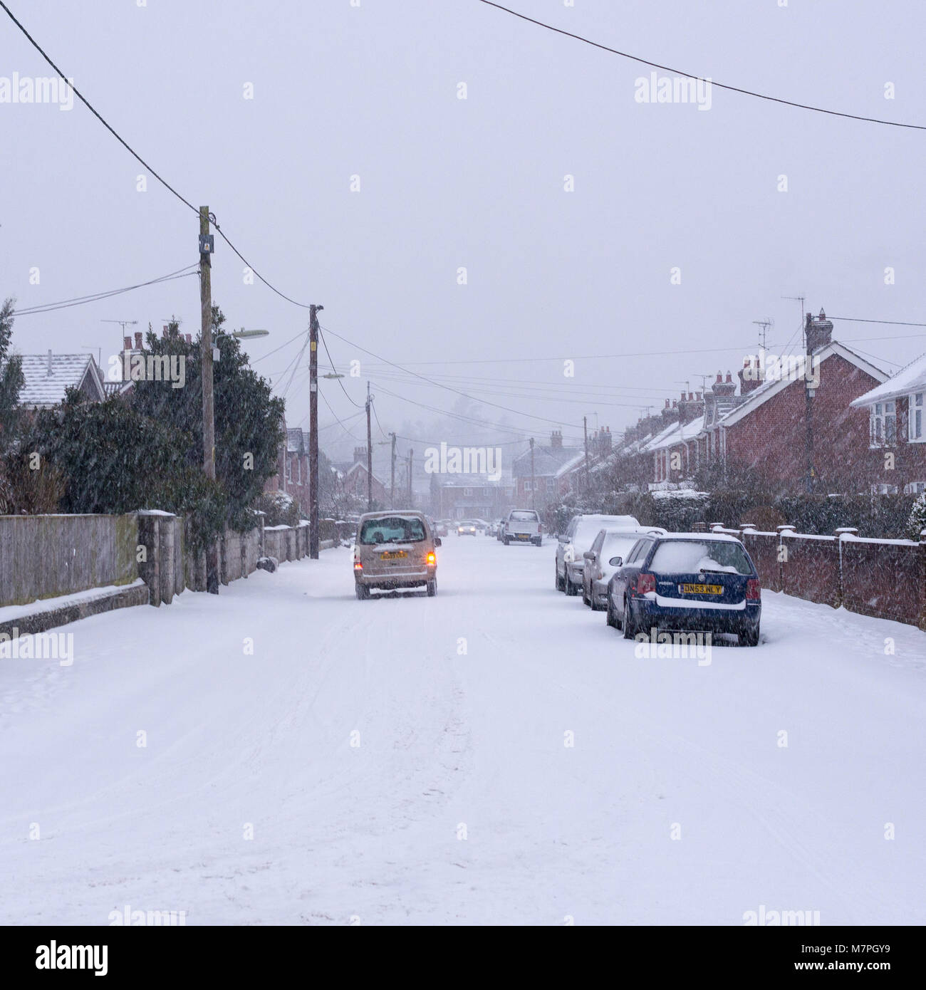 Una guida auto giù un nevoso strada suburbana in una cittadina inglese, Hampshire, Inghilterra. Foto Stock