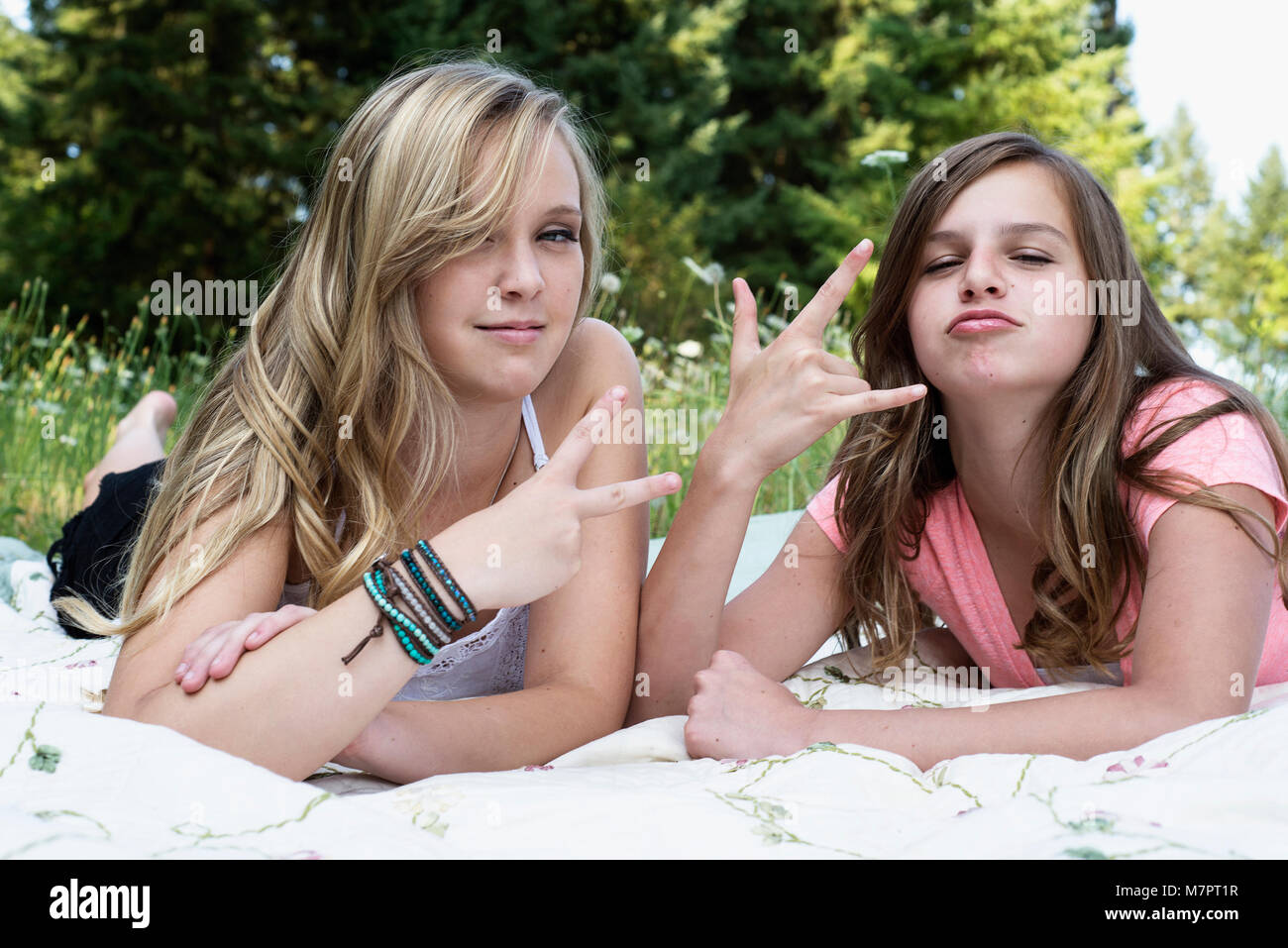 Due ragazze posa su una coperta rendendo 'pace' e 'hang loose' simboli a mano. Foto Stock