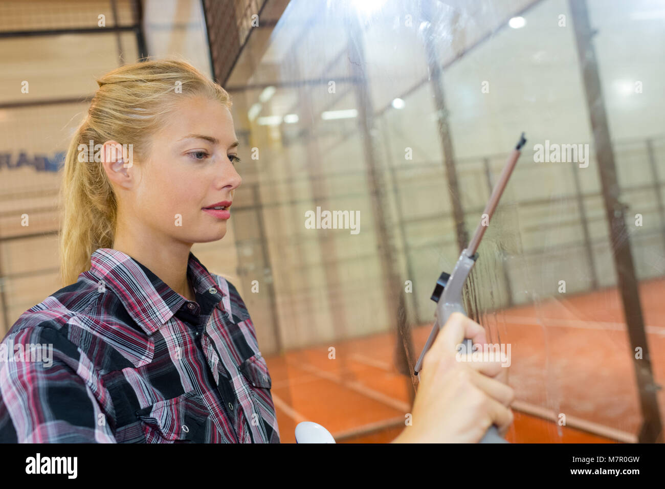 Donna di pulizia di un vetro in uno stabilimento nella Comunità Foto Stock