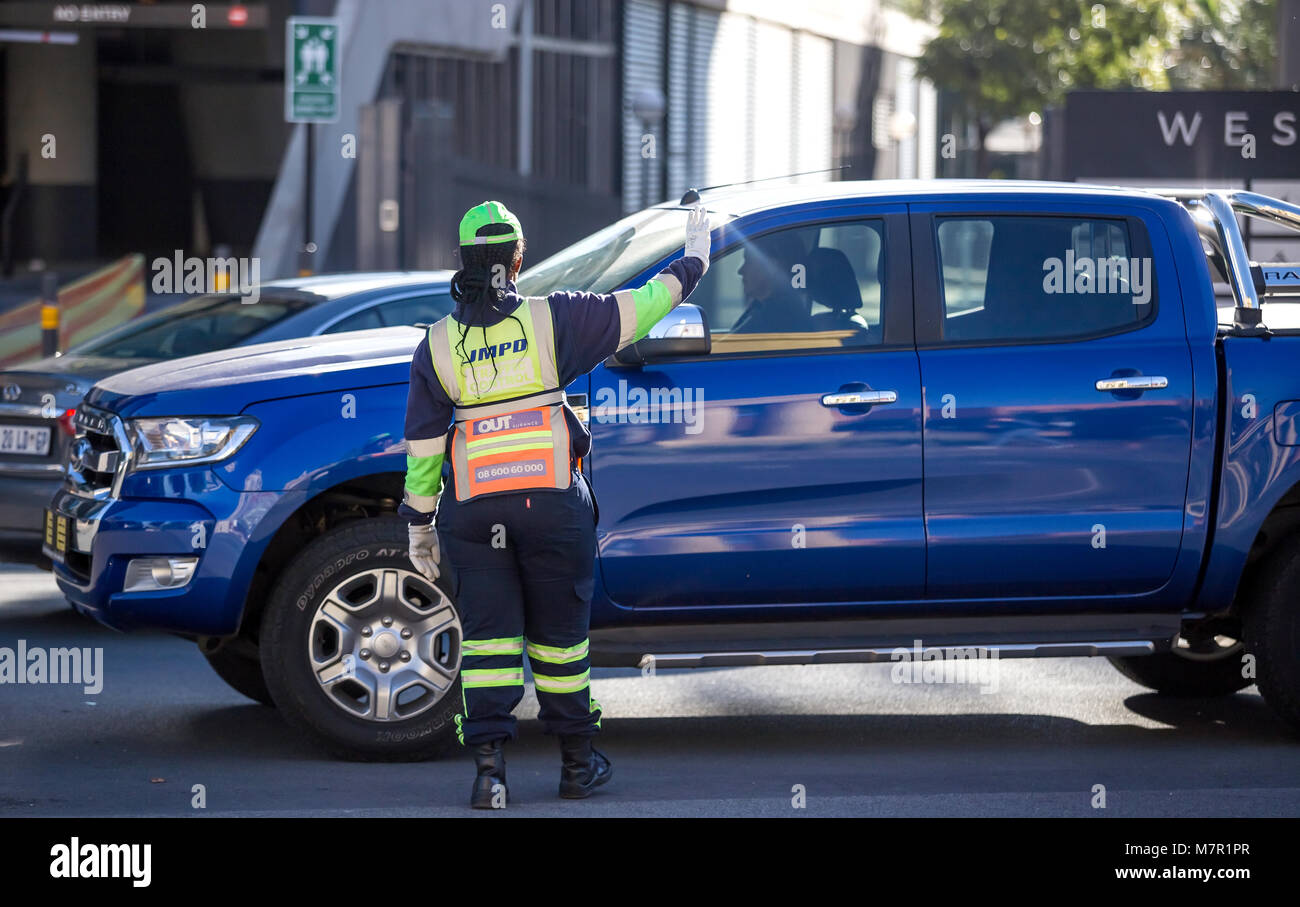 Johannesburg, Sud Africa - 8 Marzo 2018: il traffico officer tenendo la mano fino al traffico con auto in background. Foto Stock