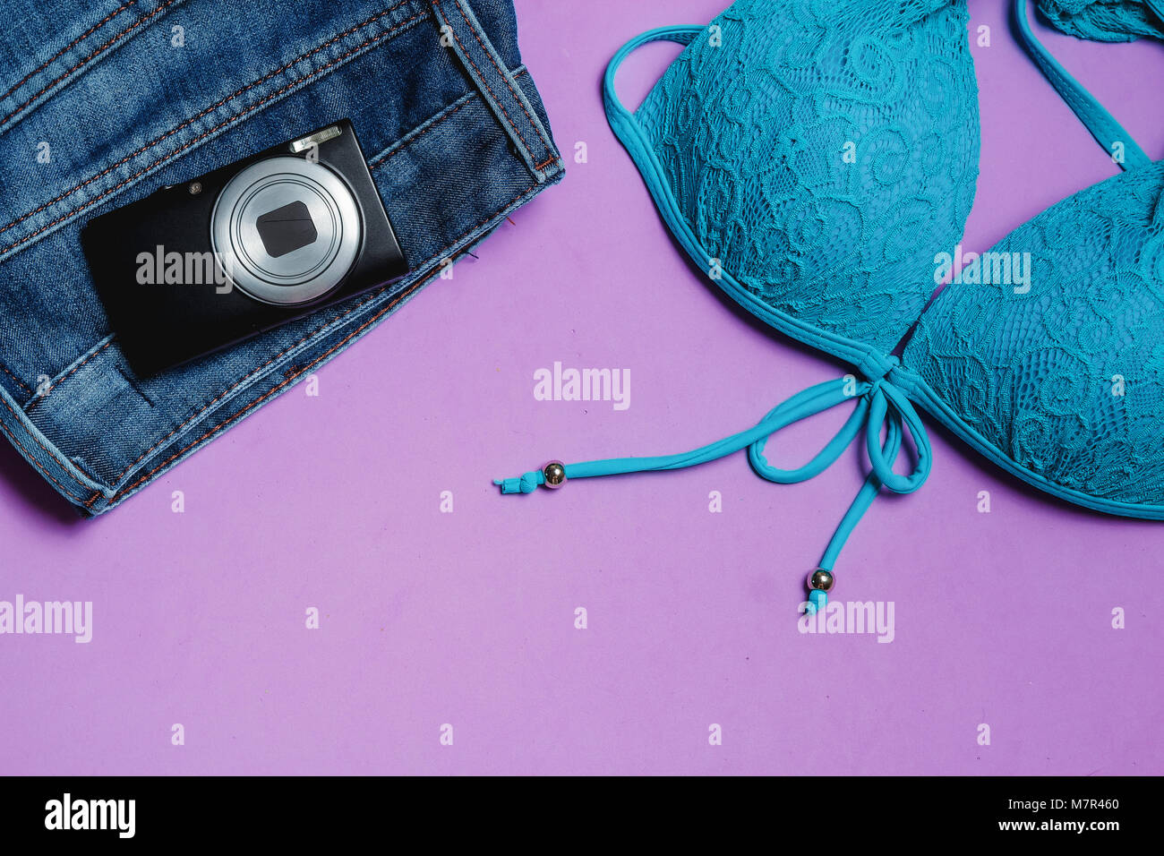 Costume da bagno, foto fotocamera su sfondo lilla. Vista dall'alto concetto di viaggio con Copyspace. Foto Stock