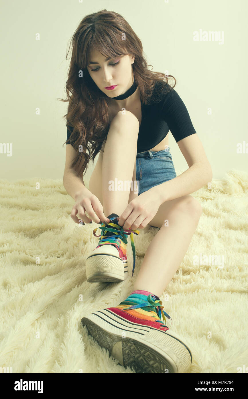 Bella ragazza mettere rainbow scarpe colorate su Foto Stock