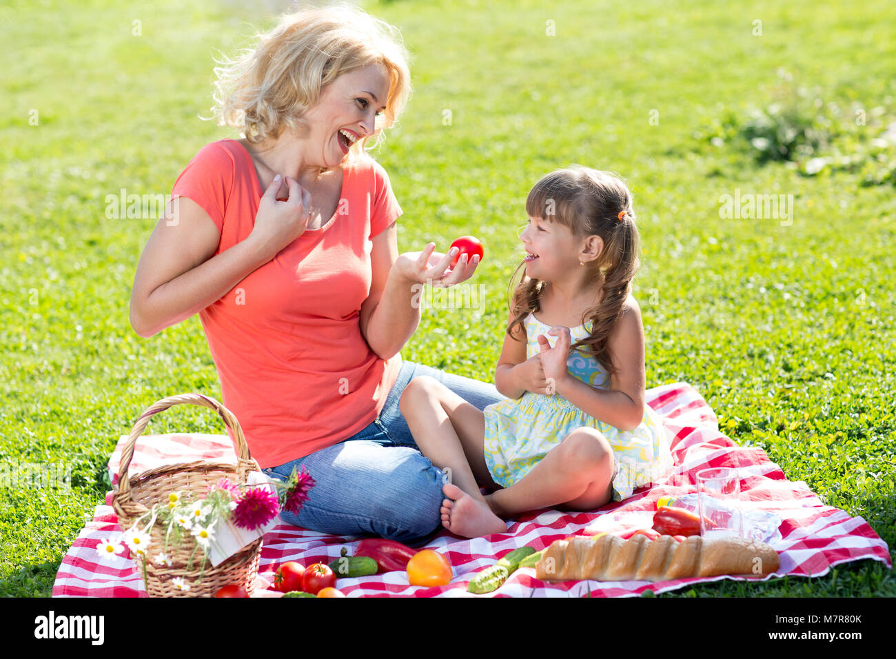 La famiglia felice - madre e figlia sul prato erboso. Picnic in vacanza estiva. Foto Stock