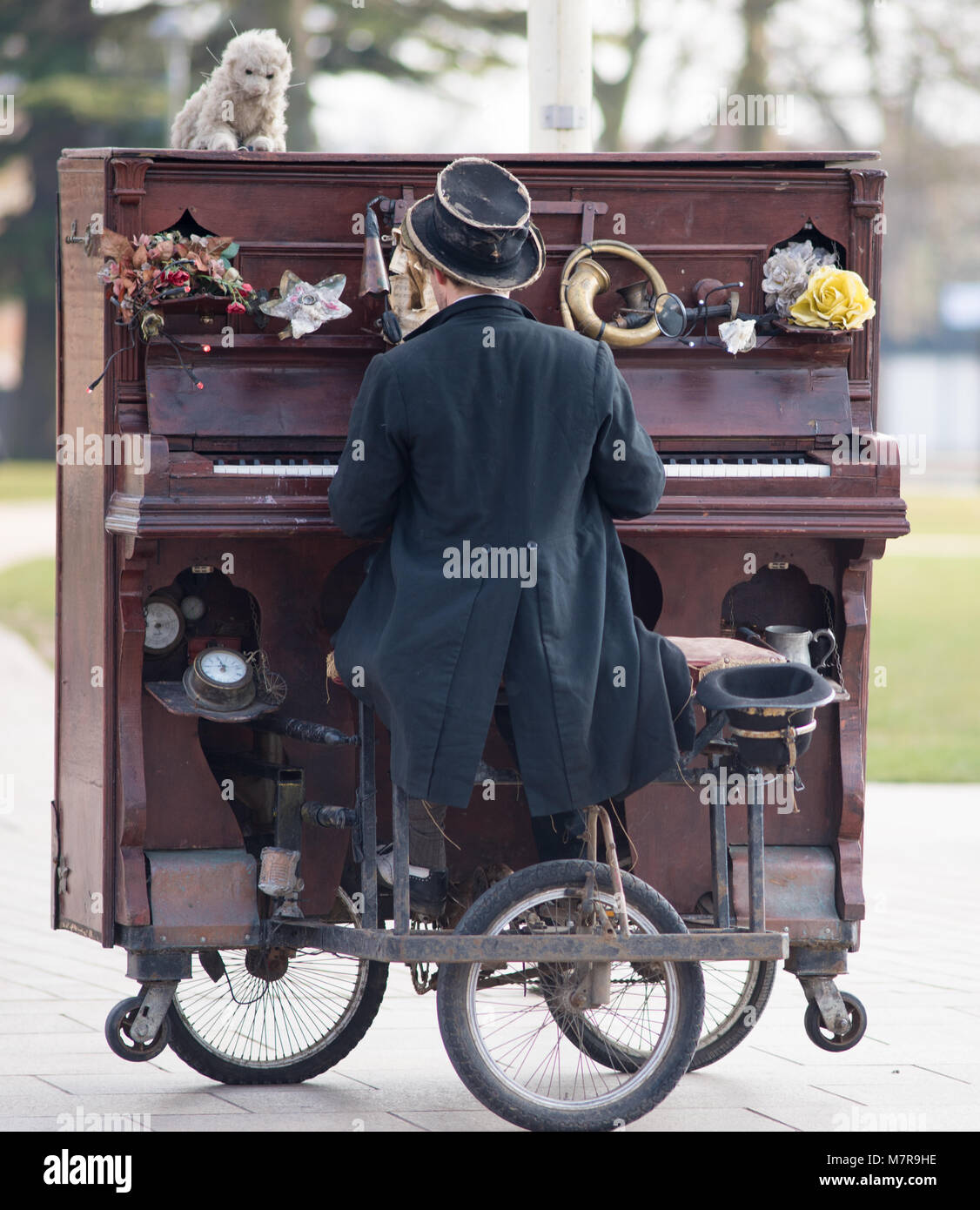 Intrattenitore in cappotto vittoriano code e top hat montante suonare il  pianoforte mobile su ruote in strada Foto stock - Alamy