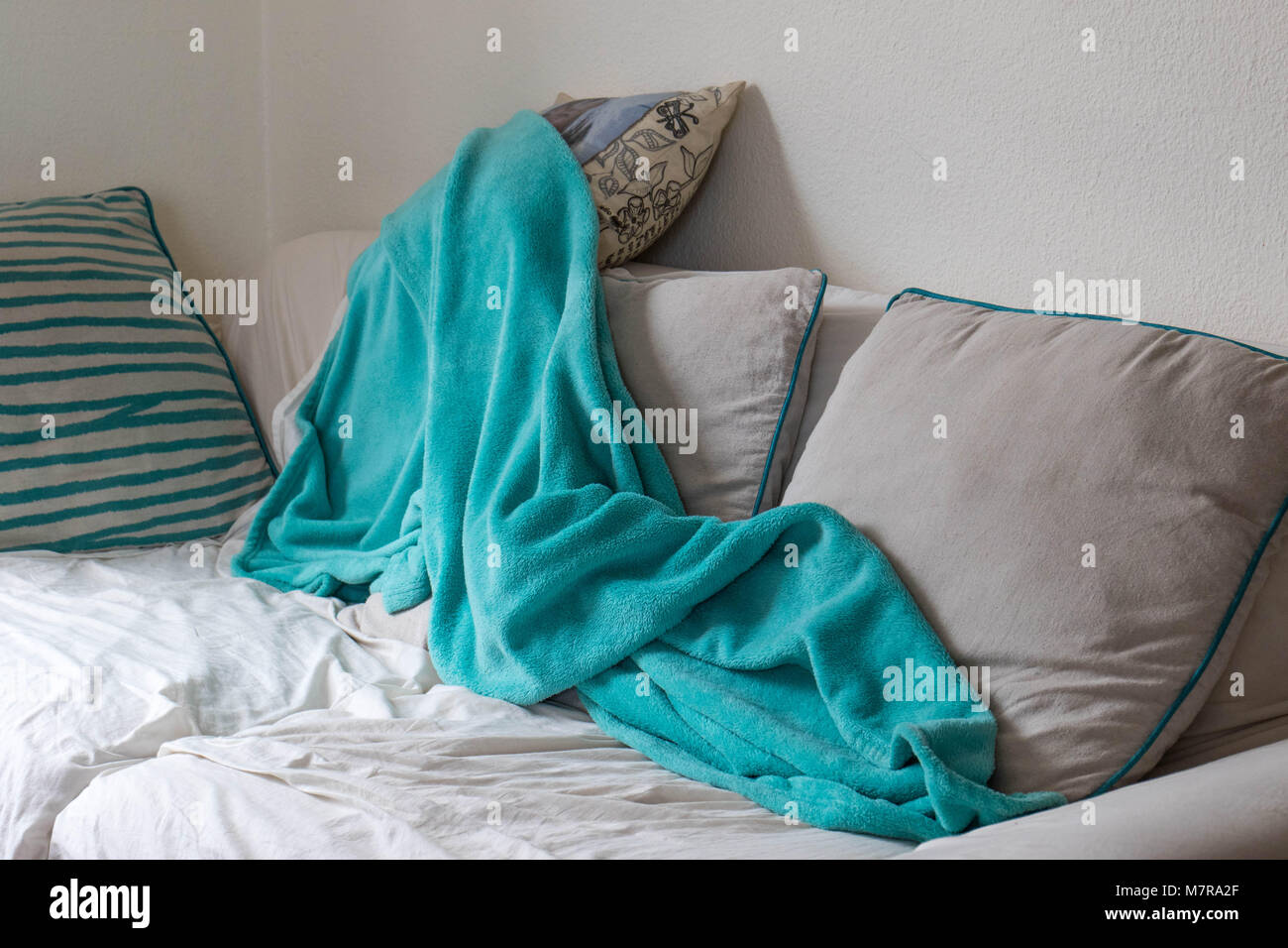 Disordinato il lettino con una coperta accartocciata che è stato utilizzato per un pisolino di immagine in formato paesaggio con spazio di copia Foto Stock