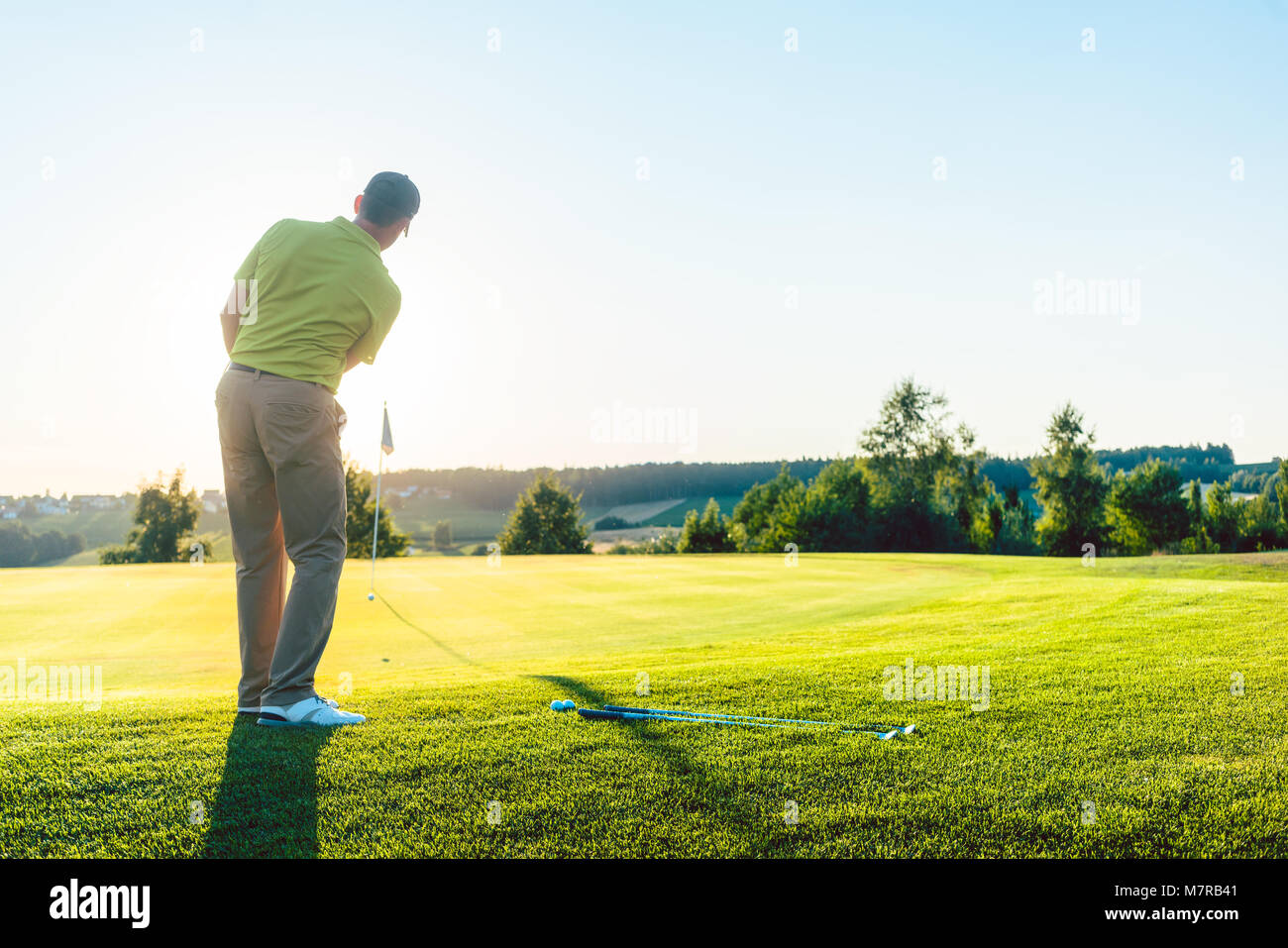 Esperto golfista maschio di colpire la pallina da golf verso la coppa Foto Stock