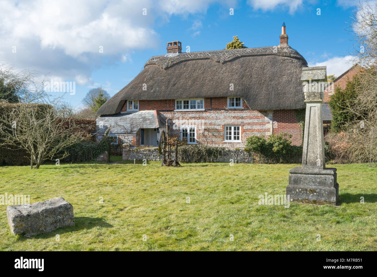 Affascinanti cottage con tetto in paglia e verde di villaggio in villaggio Martin in Hampshire, Regno Unito, con la replica 2000 croce di villaggio Foto Stock