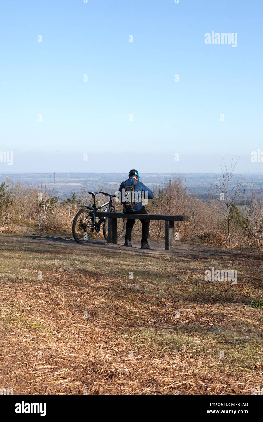 Ciclista maschio in appoggio su una panchina alla sommità del patibolo Hill Foto Stock