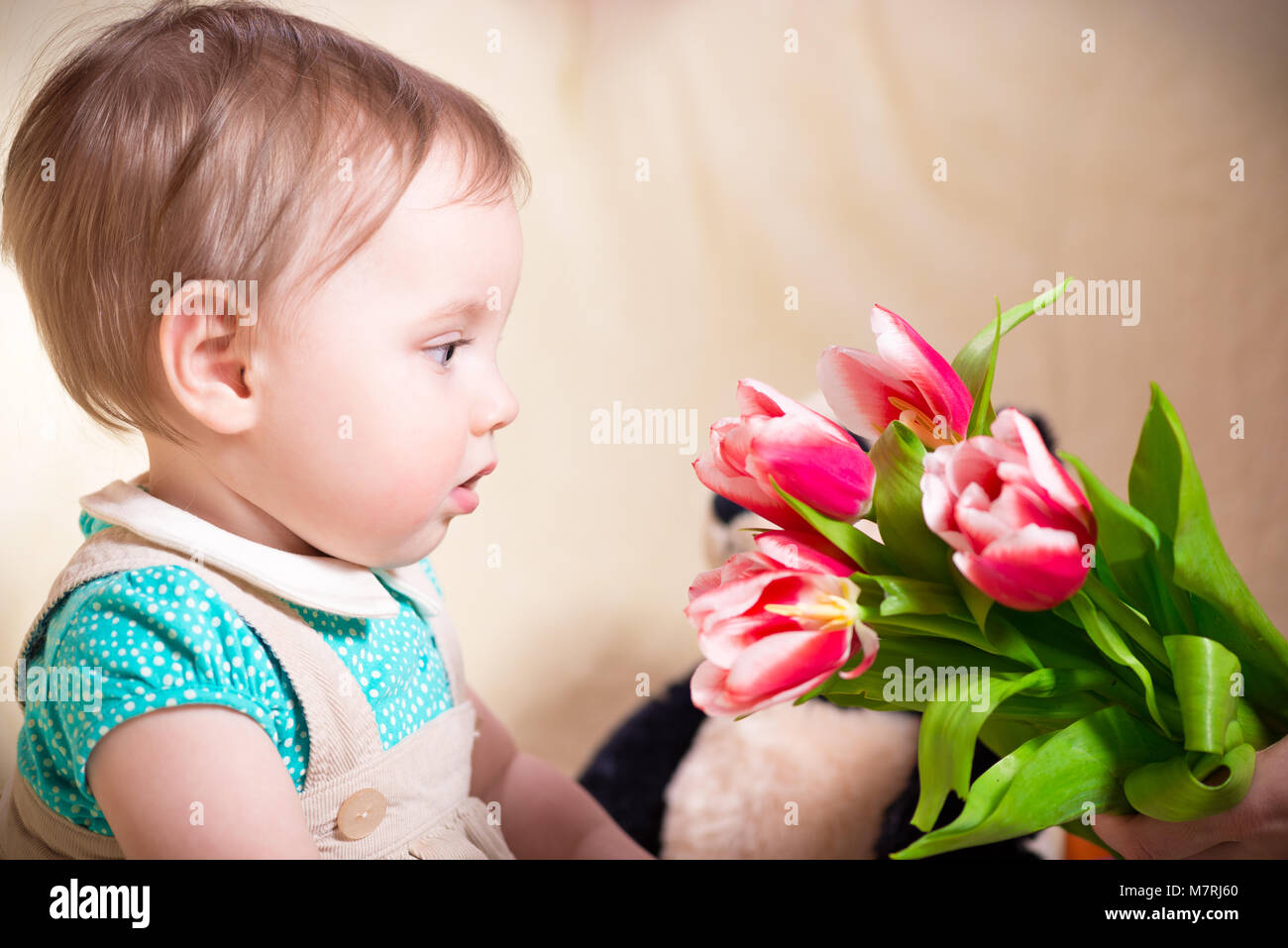 Dieci mesi Baby girl guardando i fiori Foto Stock