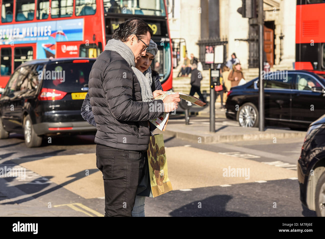 I turisti alla ricerca di mappa a Londra con il bus rosso e del traffico. Turismo. Maschio e femmina giovane. Persone. La Gran Bretagna. British. Direzioni Foto Stock