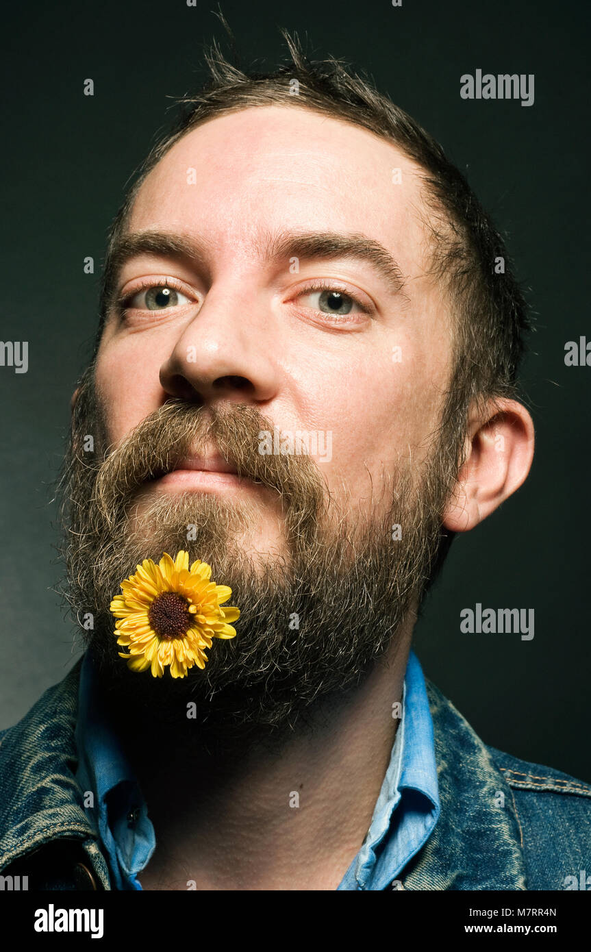 Un uomo con un fiore nella sua barba. Foto Stock