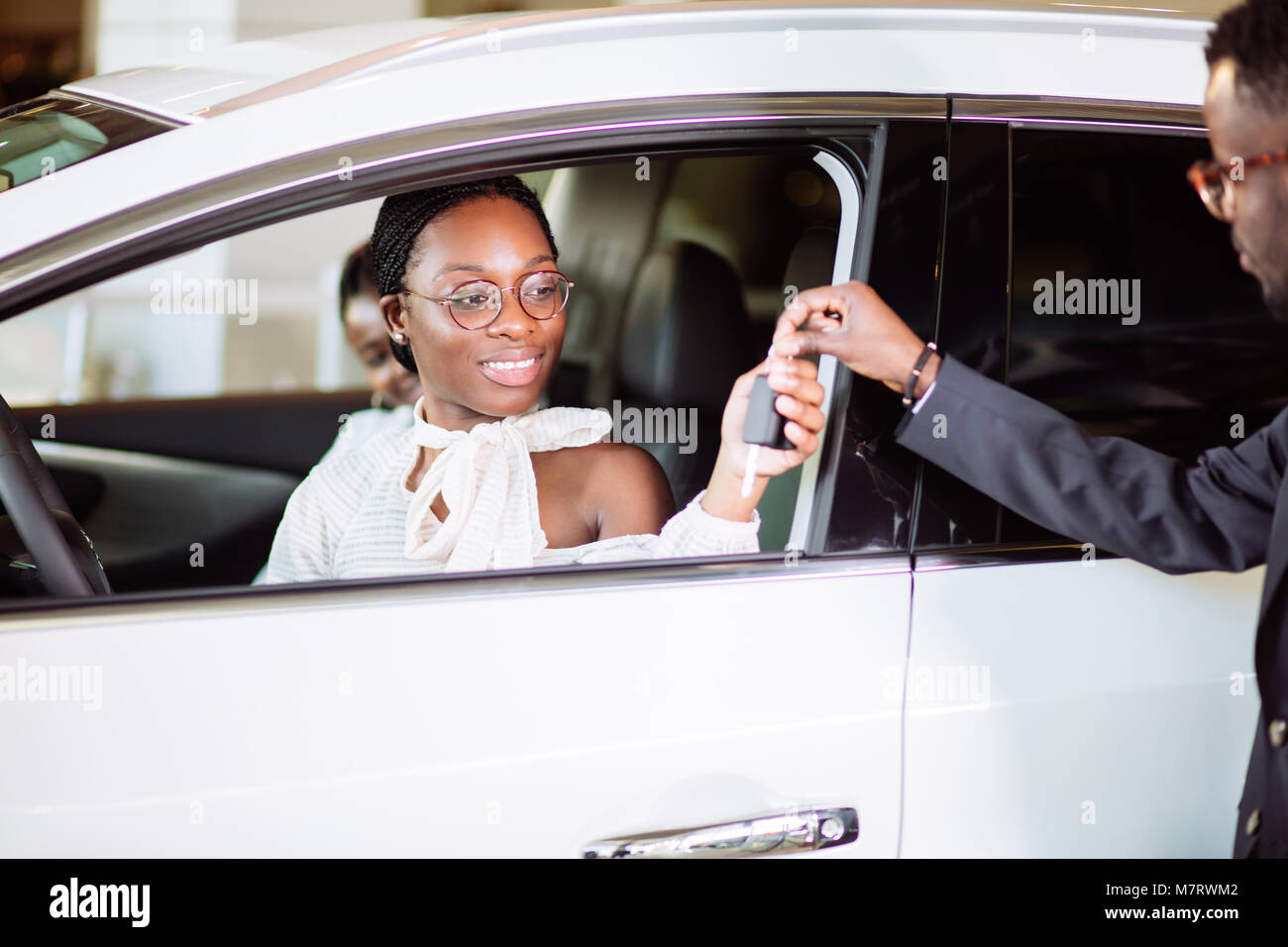 Situazione delle vendite in concessionaria auto, giovane africano coppia ottiene la chiave per la nuova vettura Foto Stock