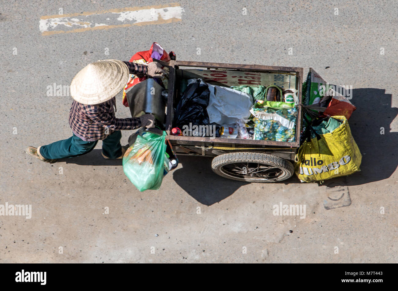 A Saigon, Vietnam, DIC 17 2017, la raccolta di rifiuti riciclabili per le strade della città di Ho Chi Minh. Donna vietnamita spingendo un carrello pieno di borse, Saigon Foto Stock