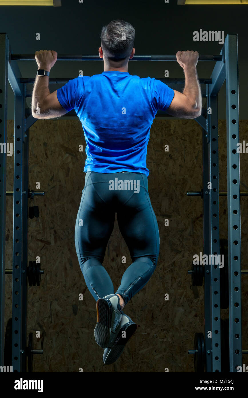 L'atleta tira se stesso sulla barra nella palestra vista dal retro Foto Stock