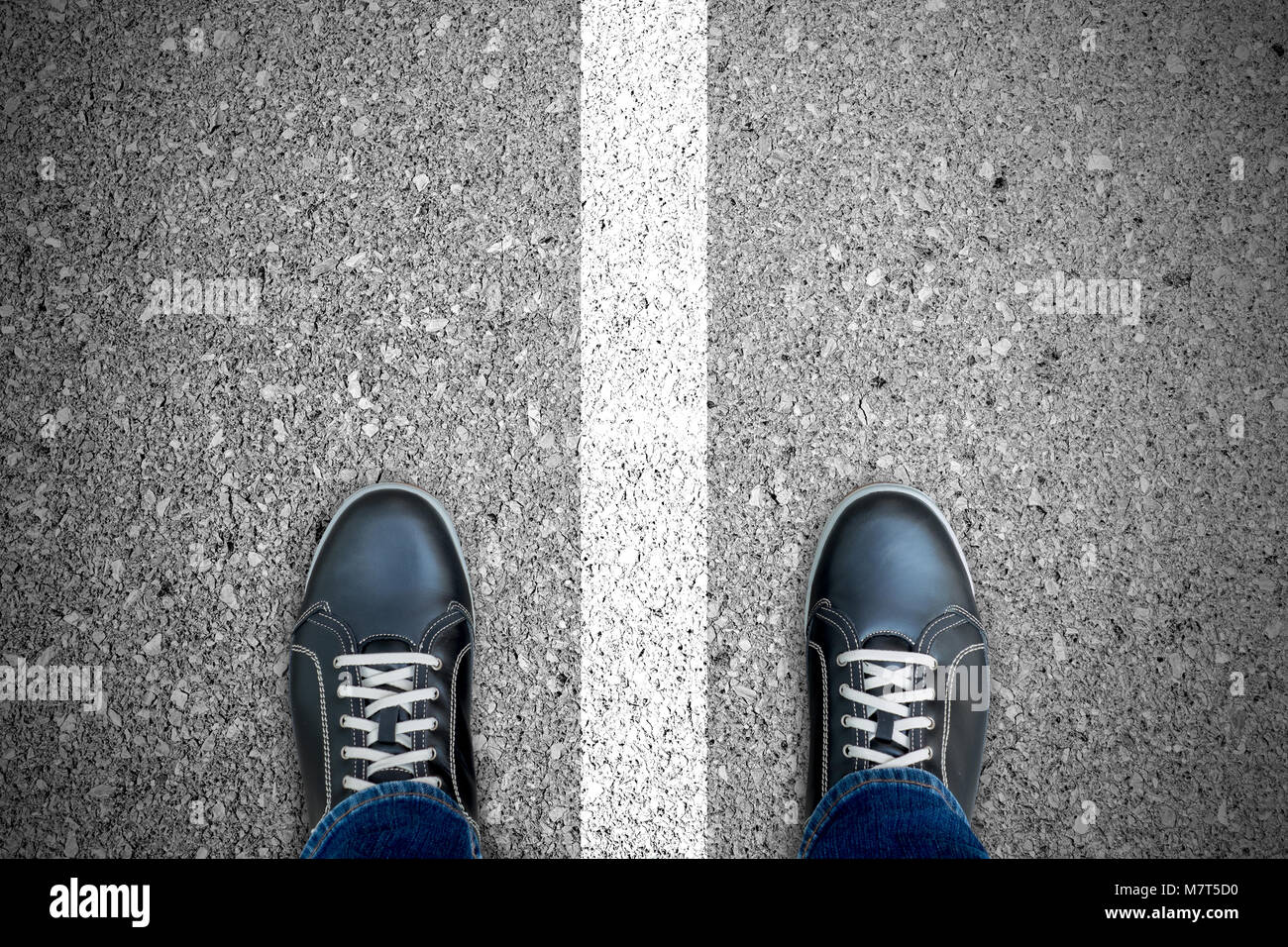 Nero scarpe casual in piedi sopra la linea bianca che separano a sinistra e  a destra. In piedi su entrambi i lati. Giusto e sbagliato. Il bene e il  male Foto stock -