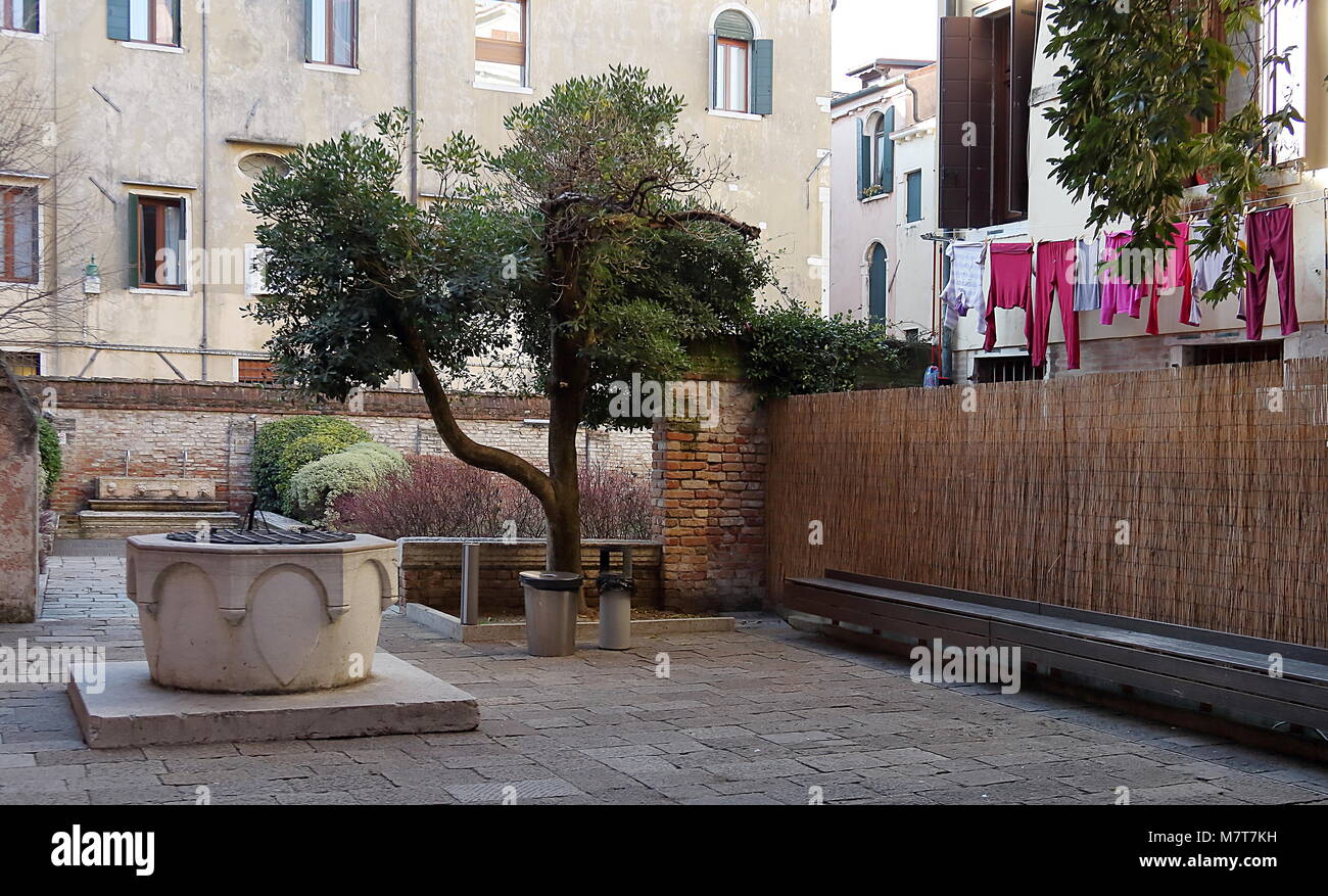 Venezia, Italia. Corte con pozzo, edifici storici, biancheria e indumenti in Santa Croce Foto Stock