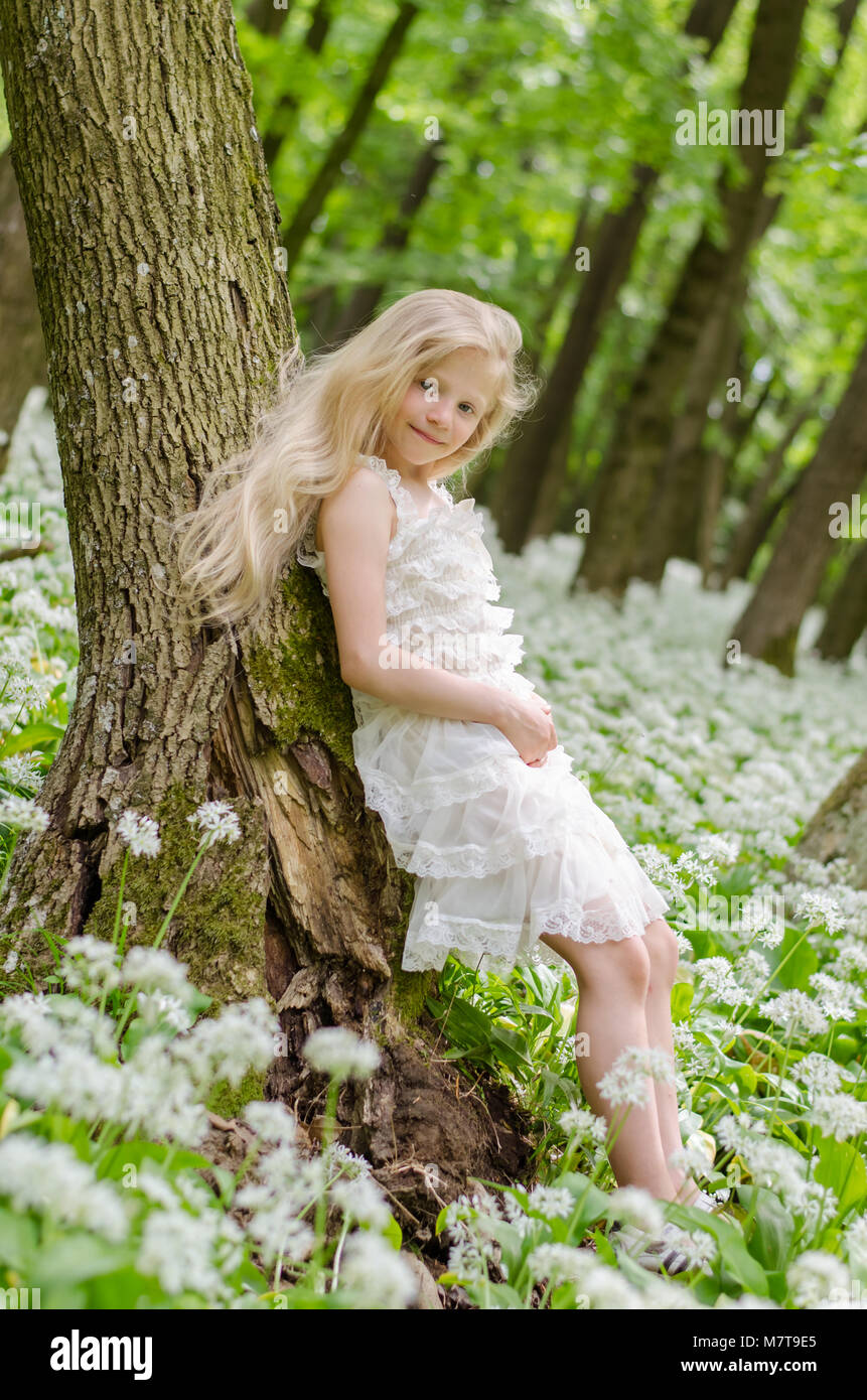 Bella fata ragazza con lunghi capelli biondi nella foresta di primavera Foto Stock