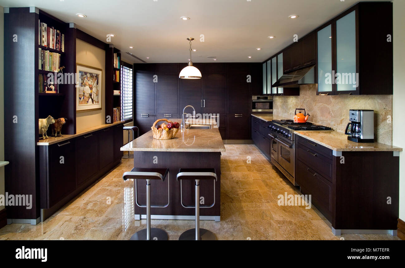 Di legno marrone scuro e mobili da cucina e un'isola con piano in granito  Foto stock - Alamy