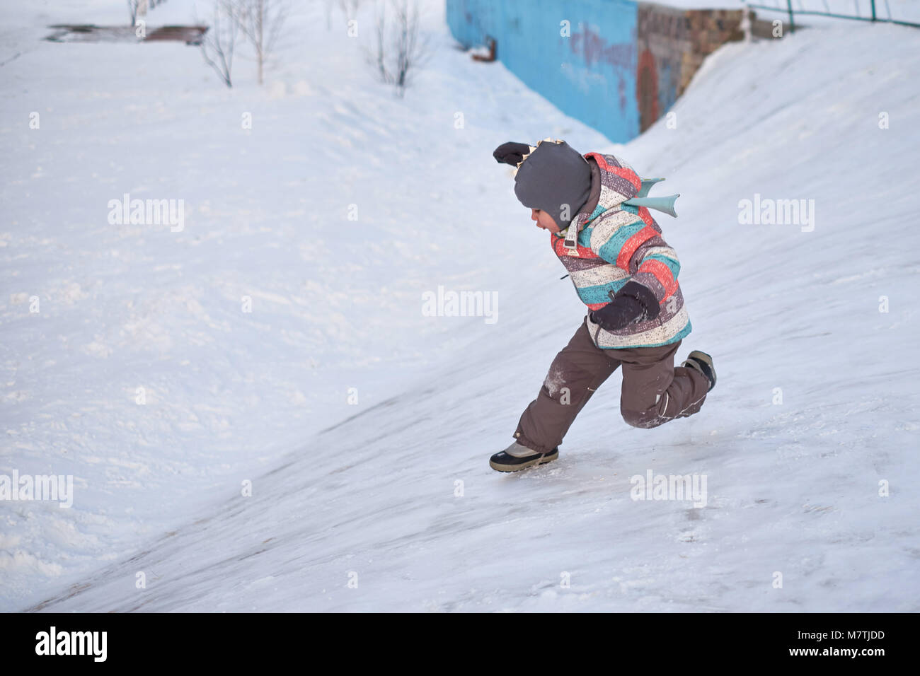 Funny capretto piccolo ragazzo in abiti colorati giocare all'aperto in inverno nelle fredde giornate innevate. Bambino felice divertirsi e giocare con la neve Foto Stock