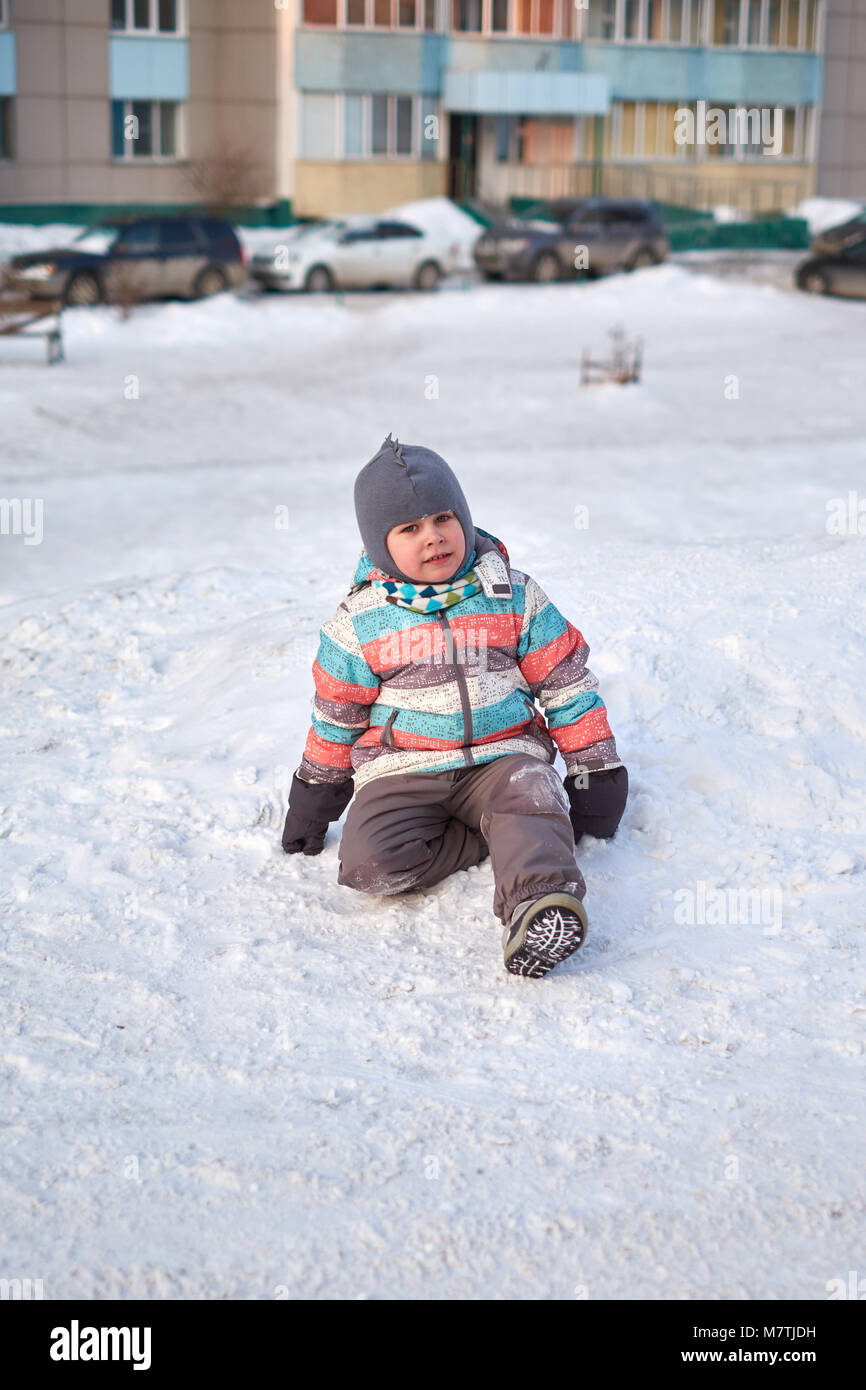 Funny capretto piccolo ragazzo in abiti colorati giocare all'aperto in inverno nelle fredde giornate innevate. Bambino felice divertirsi e giocare con la neve Foto Stock