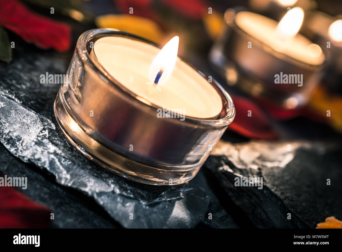 2 candele romantiche su ardesia con petali di rosa e foglie Foto