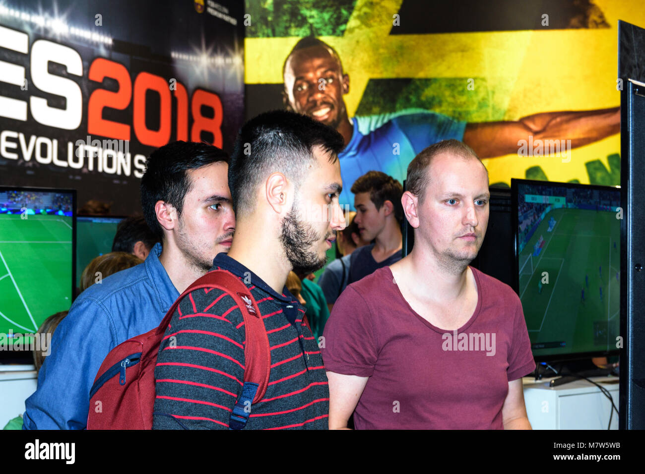 Colonia, Germania - 24 agosto 2017: Tre visitatori fiera di guardare uno schermo presso lo stand di Pro Evolution Soccer da società Konami a Gamescome 2017. Foto Stock