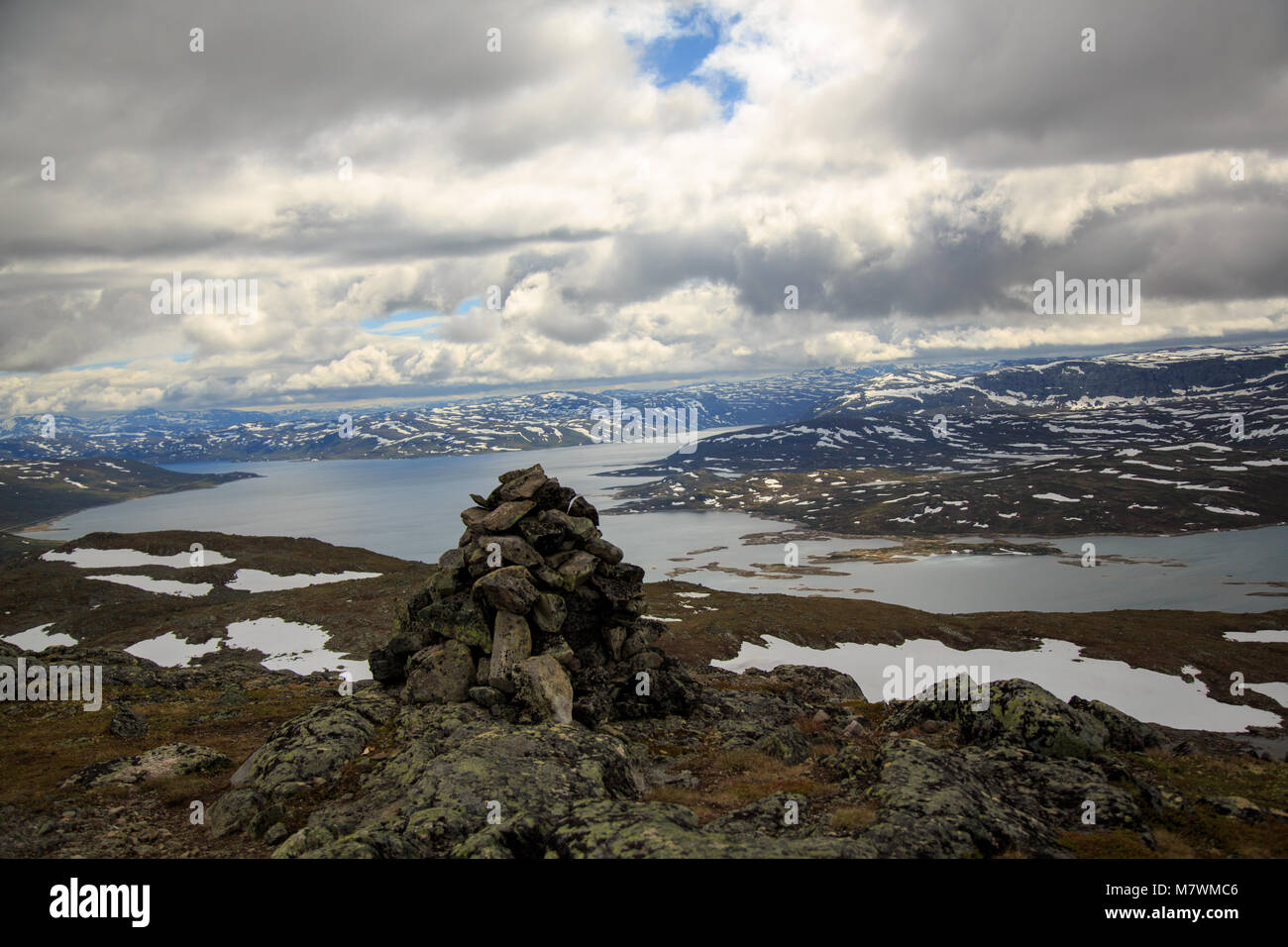 Cairn in cima a una montagna e la vista del lago e della catena montuosa di Jotunheimen Norvegia Foto Stock