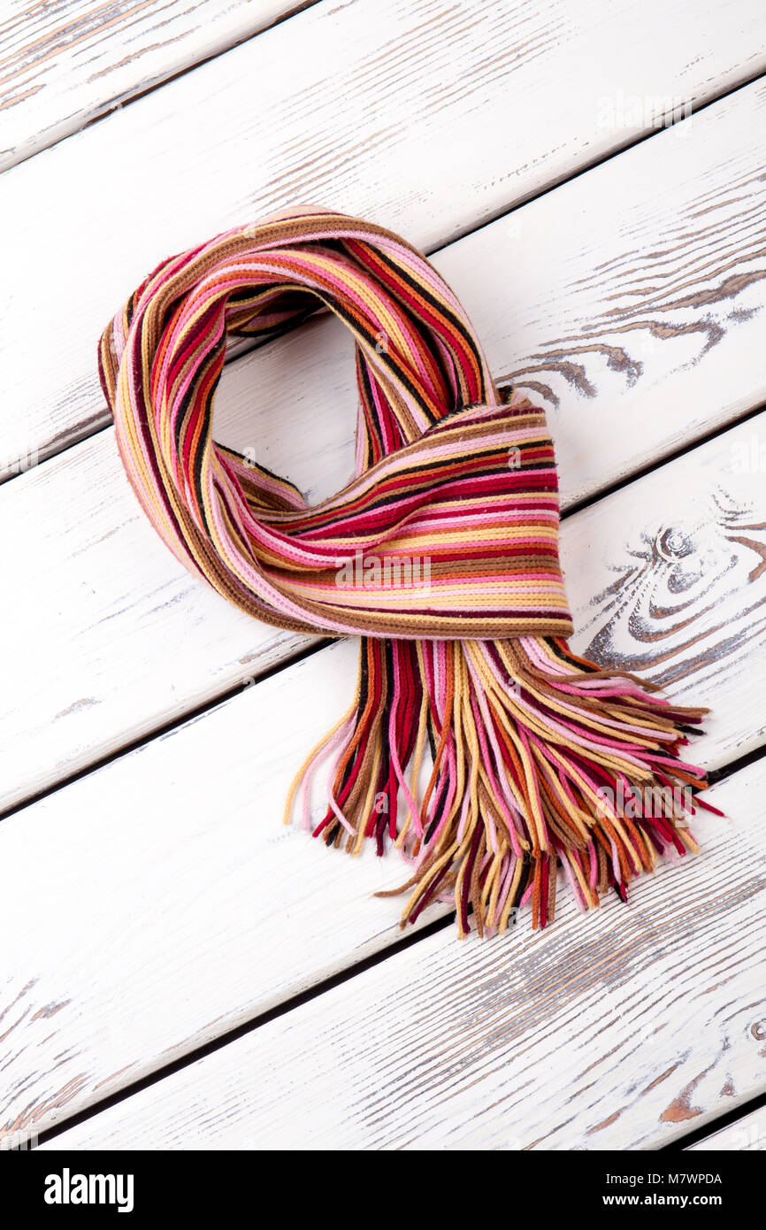 La lana sciarpa in cavo intrecciato a maglia. Bianco scrivanie in legno sfondo di superficie. Foto Stock