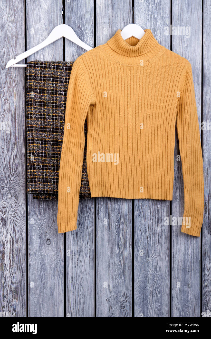Donna abiti invernali sulle staffe. Maglione giallo e scacchi pantaloni di  lana. Legno scuro superficie scrivania sfondo Foto stock - Alamy