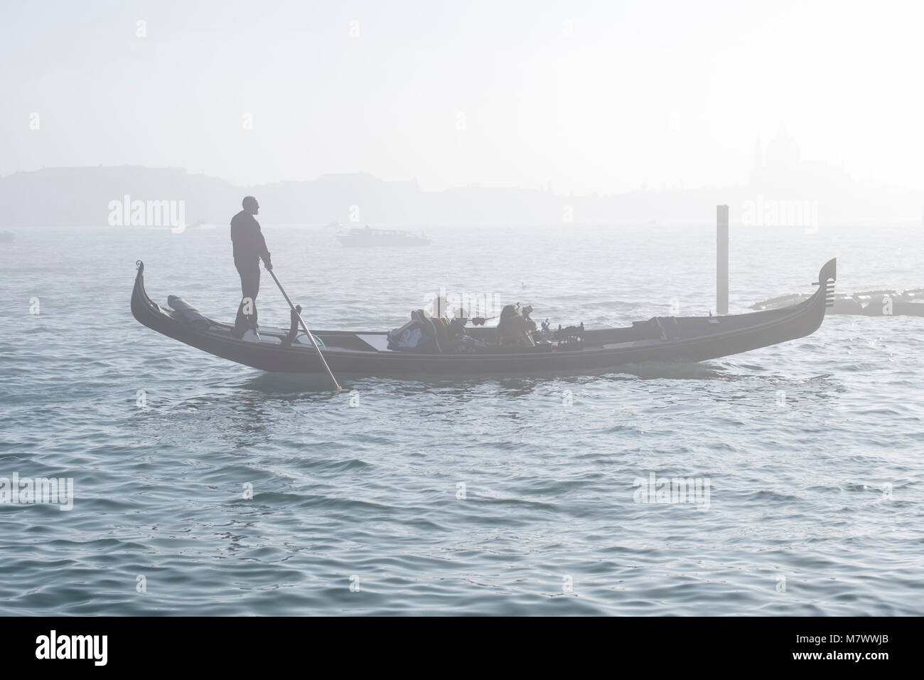 Venezia, Italia: Gondoliere guida i suoi ospiti attraverso la nebbia Foto Stock