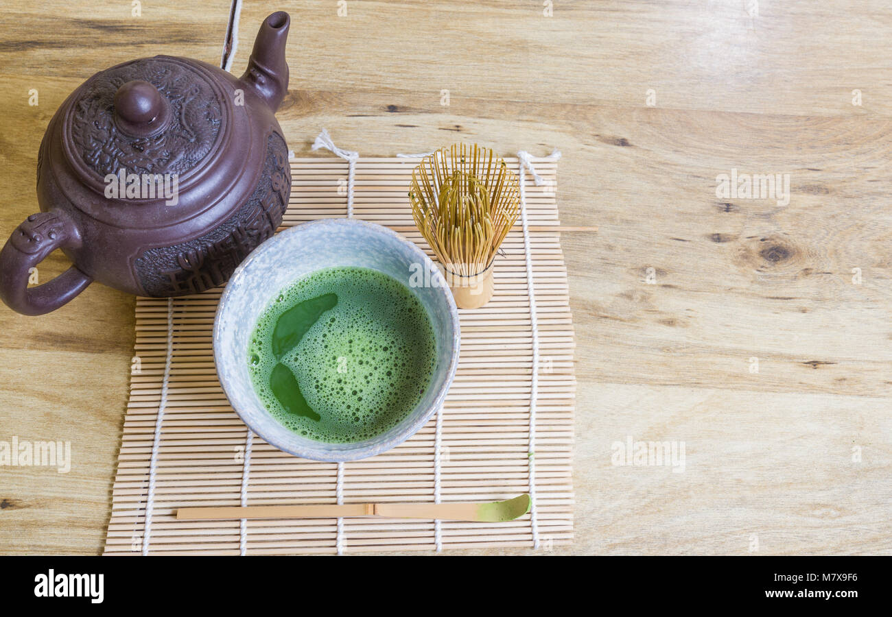 Al di sopra di vista della cerimonia del tè giapponese elementi comprendenti un recipiente in pietra di tè verde Matcha, mescolando con una frusta di bambù, scoop, e di un marrone teiera asiatici sul tappetino di bambù. Foto Stock Al di sopra di vista della cerimonia del tè giapponese elementi comprendenti un recipiente in pietra di tè verde Matcha, mescolando con una frusta di bambù, scoop, e di un marrone teiera asiatici sul tappetino di bambù. Foto Stock