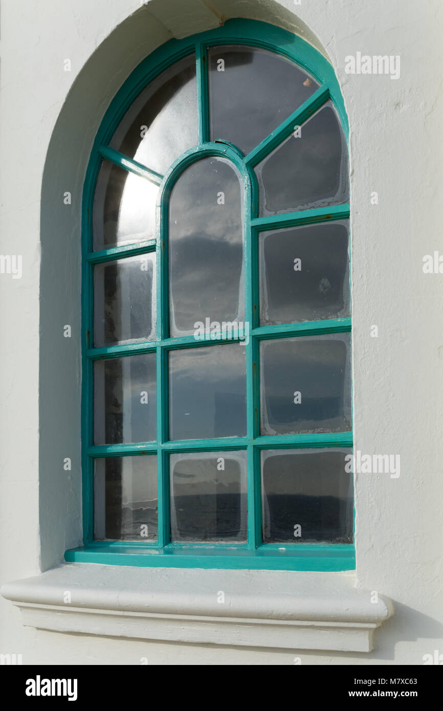 Una finestra ad arco in Re Giorgio V colonnato con una cornice di verde e ampia cornice intonacata; sole su due dei riquadri, Bexhill-on-Sea Foto Stock