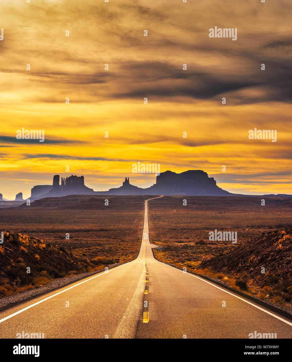 Deserto strada che conduce alla valle del monumento al tramonto Foto Stock