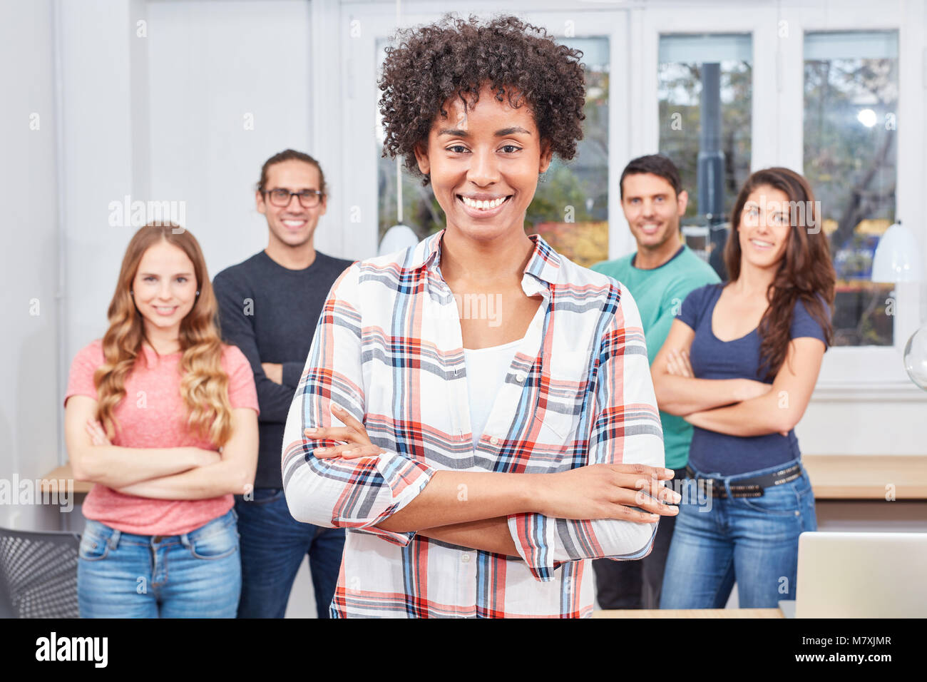 Giovane studente multiculturale come un business di successo di donna di fronte il suo team Foto Stock