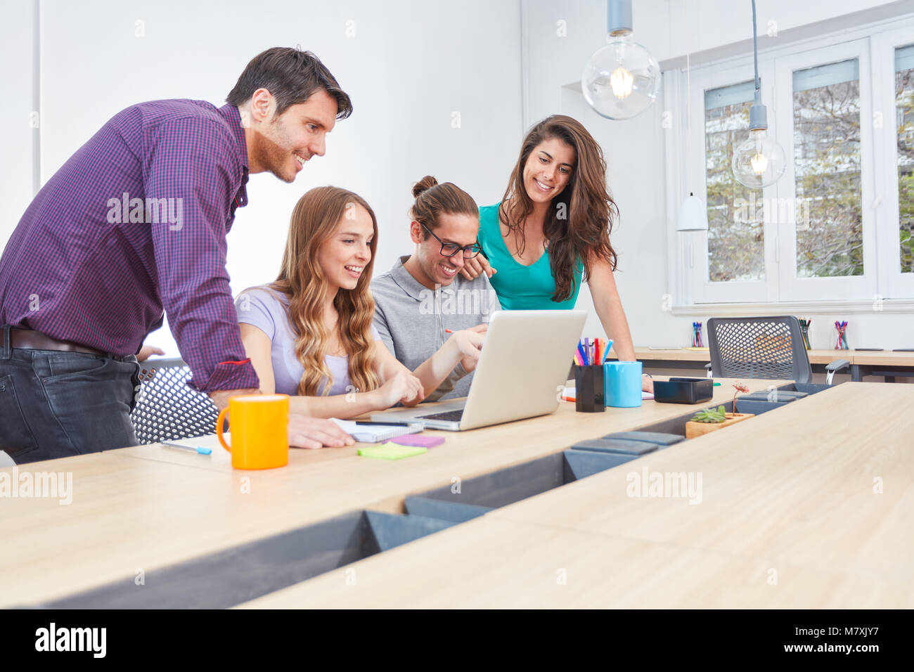 Giovani internet start-up team ha divertimento insieme sul computer portatile in ufficio coworking Foto Stock