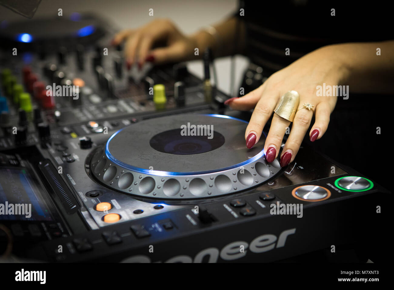 DJ femmina con le unghie rosse su CDJ e mixer. Foto Stock