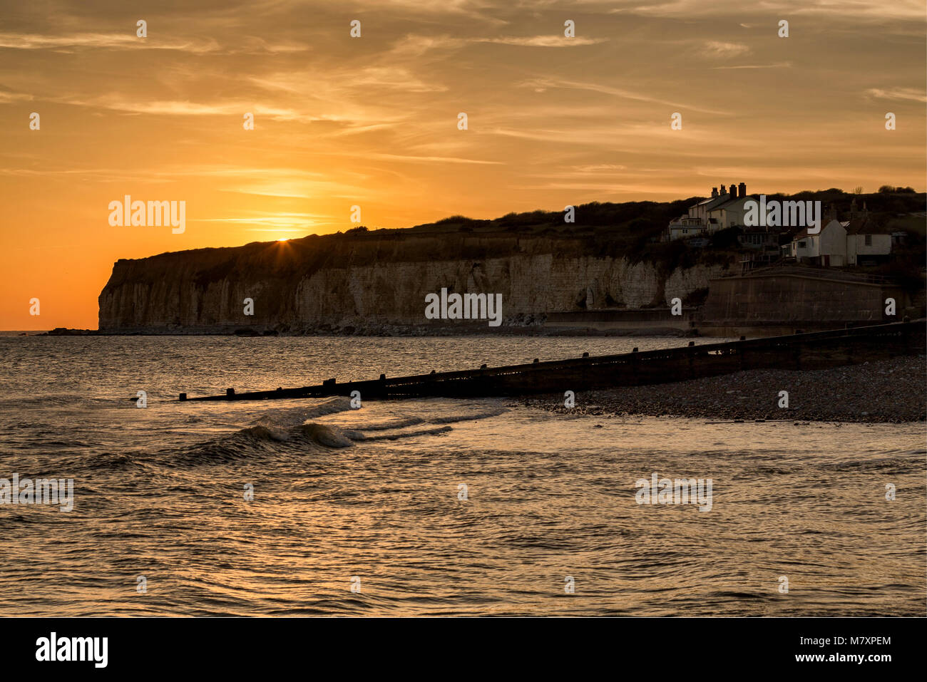 EAST SUSSEX, Regno Unito - FEB 2018: Coastguard Cottages con il sole che tramonta dietro le scogliere di gesso Foto Stock