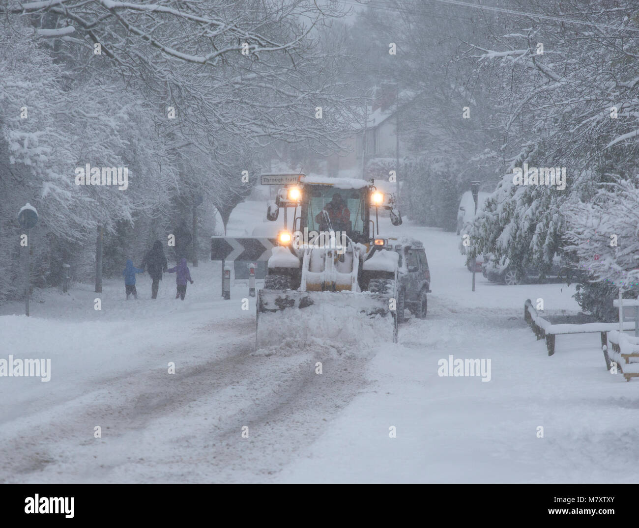Un trattore con un aratro di neve cancellazione di una strada a Redditch, Worcestershire, Regno Unito. Foto Stock