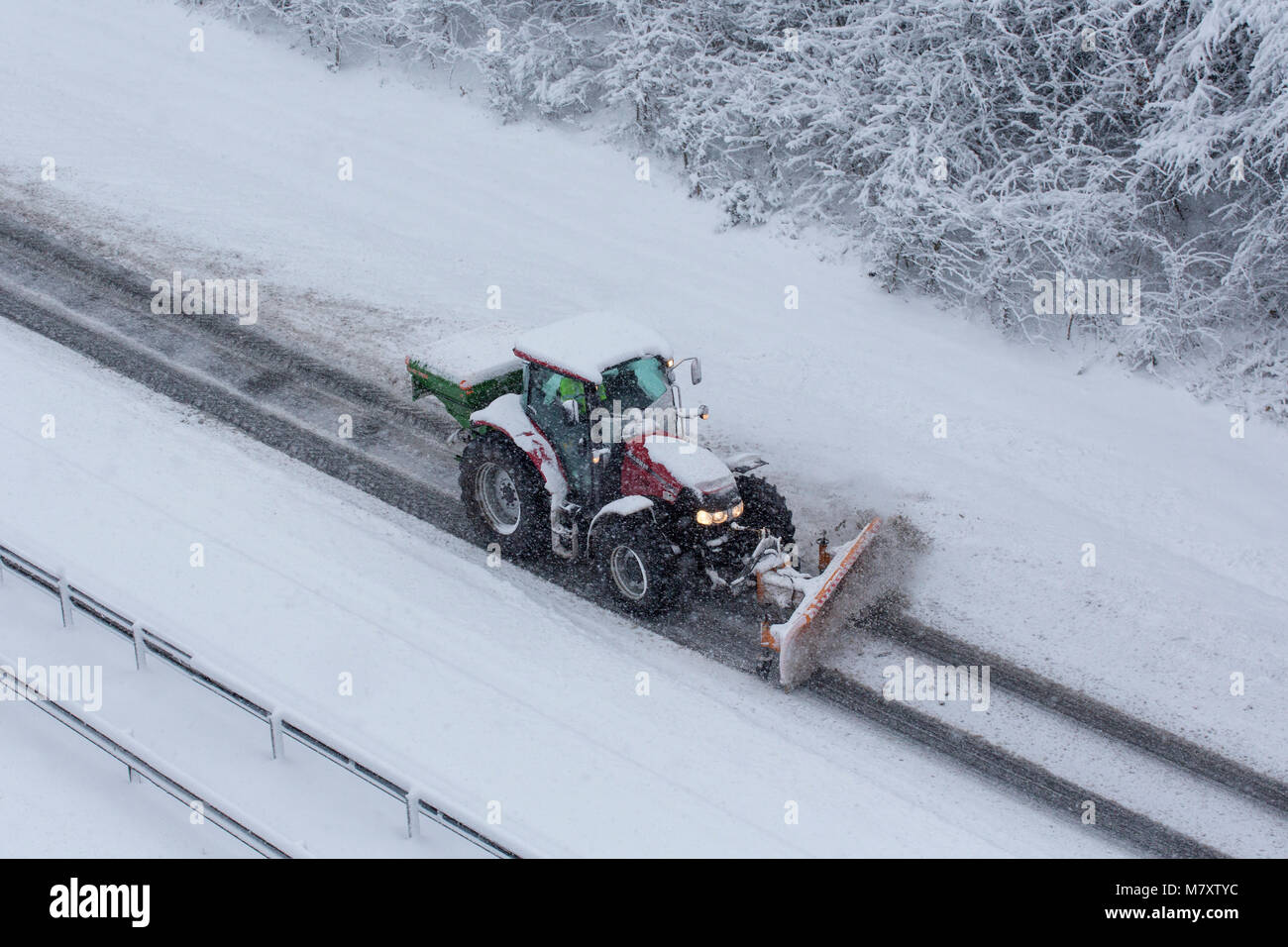 Un trattore la rimozione di neve da una strada a doppia carreggiata a Redditch, Worcestershire, Regno Unito Foto Stock